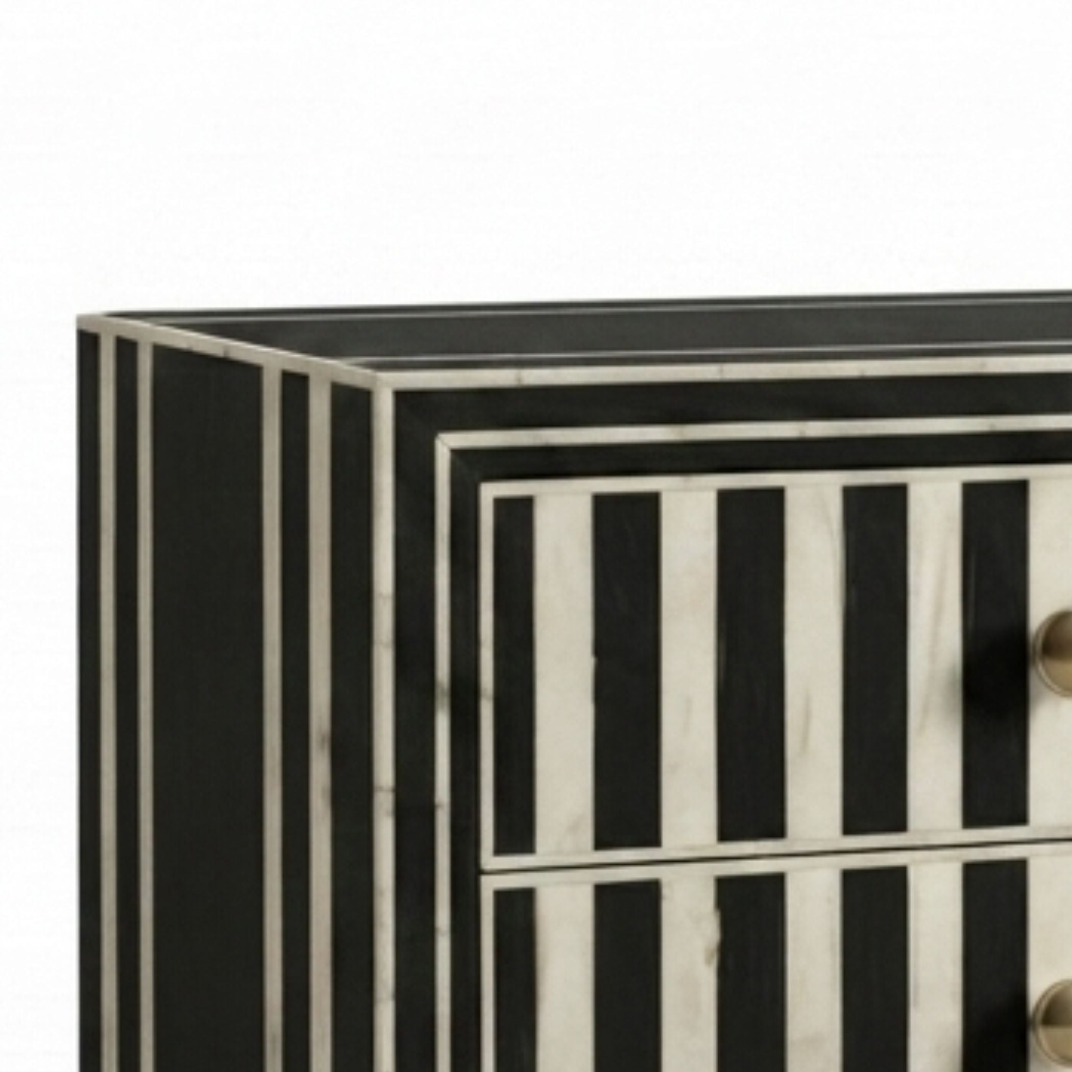 Close-up of a striped chest of drawers with black and white bone-inlay style panels and small round metallic knobs, shown against a plain white background.