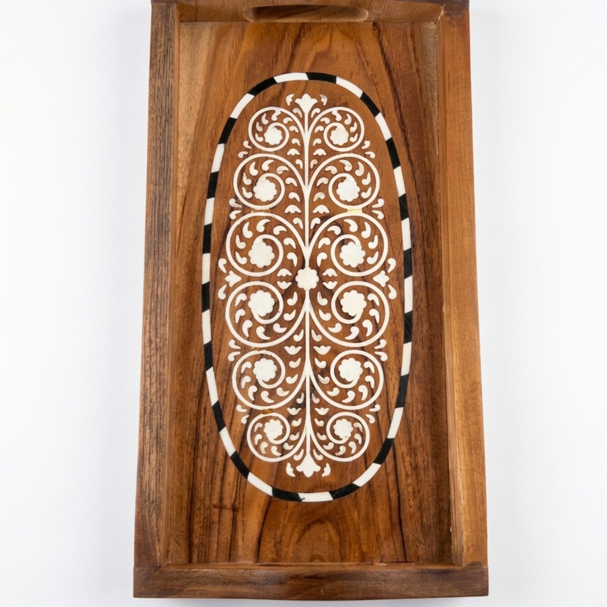 A rectangular wooden serving tray with a carved oval inlay featuring white floral scrollwork and a black-and-white striped border, shown against a plain white background.
