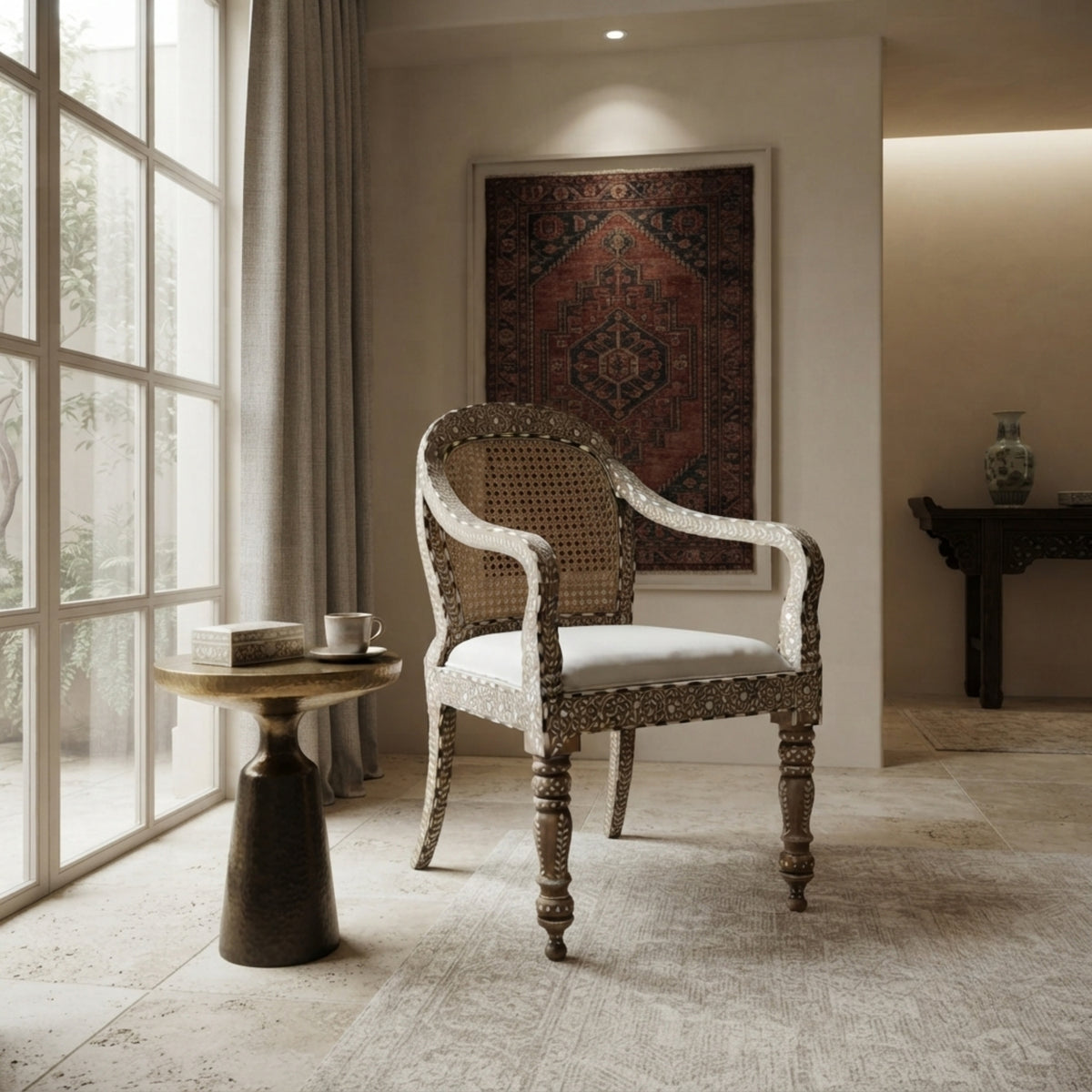 A classic armchair with a carved wooden frame, woven cane backrest, and white upholstered seat, styled in a bright, modern room next to a small round side table.