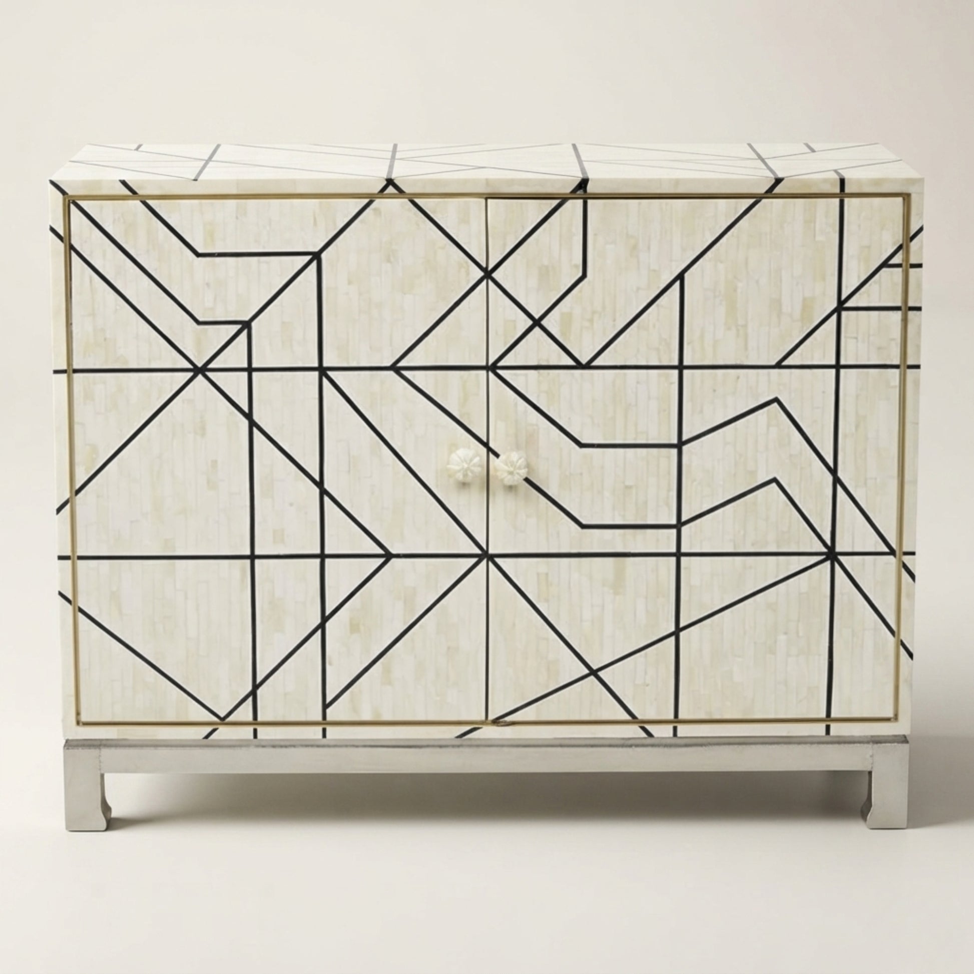 A two-door sideboard cabinet featuring a cream-colored bone-in-shell textured finish with a black geometric line pattern, gold trim, and a white marble top and base.