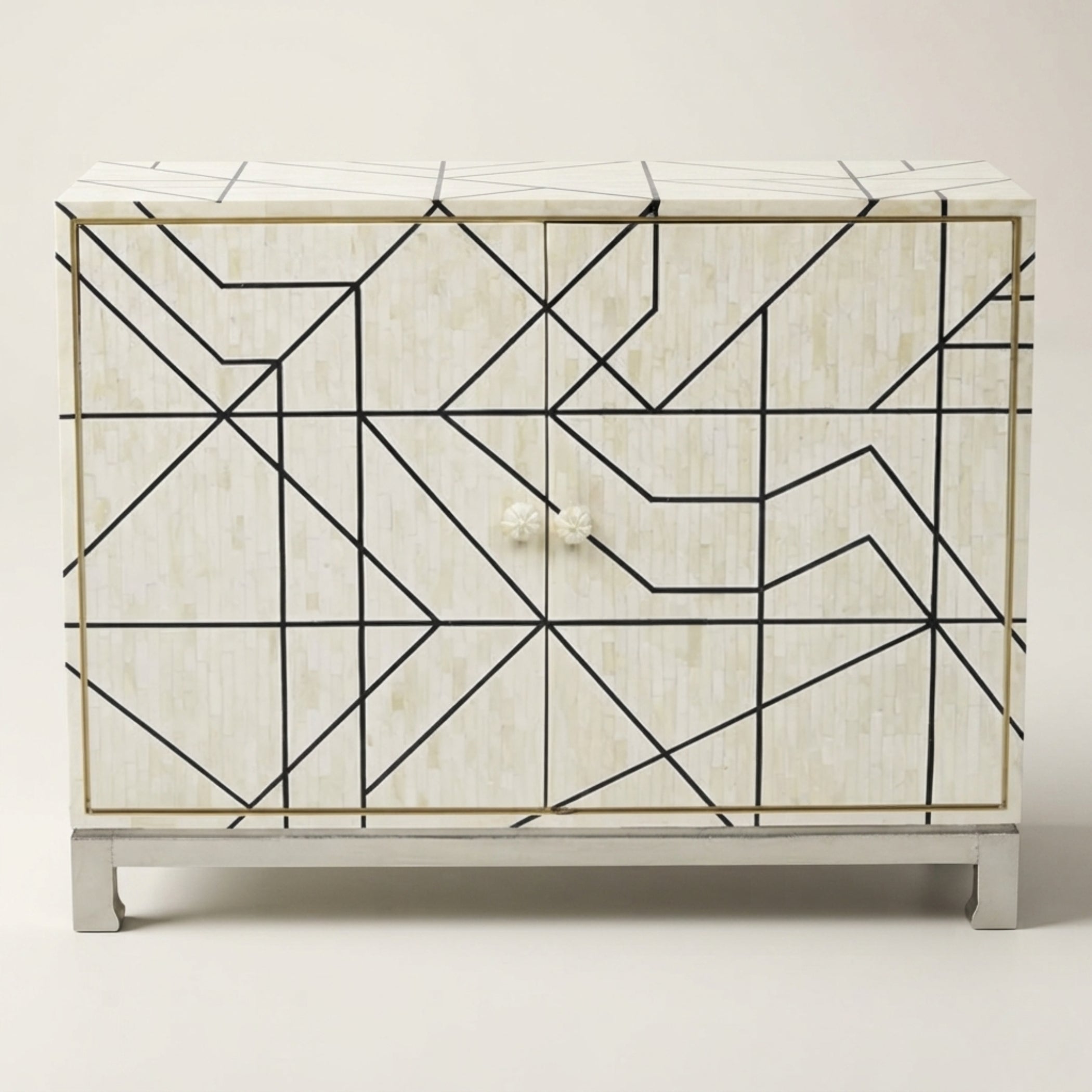A two-door sideboard cabinet featuring a cream-colored bone-in-shell textured finish with a black geometric line pattern, gold trim, and a white marble top and base.