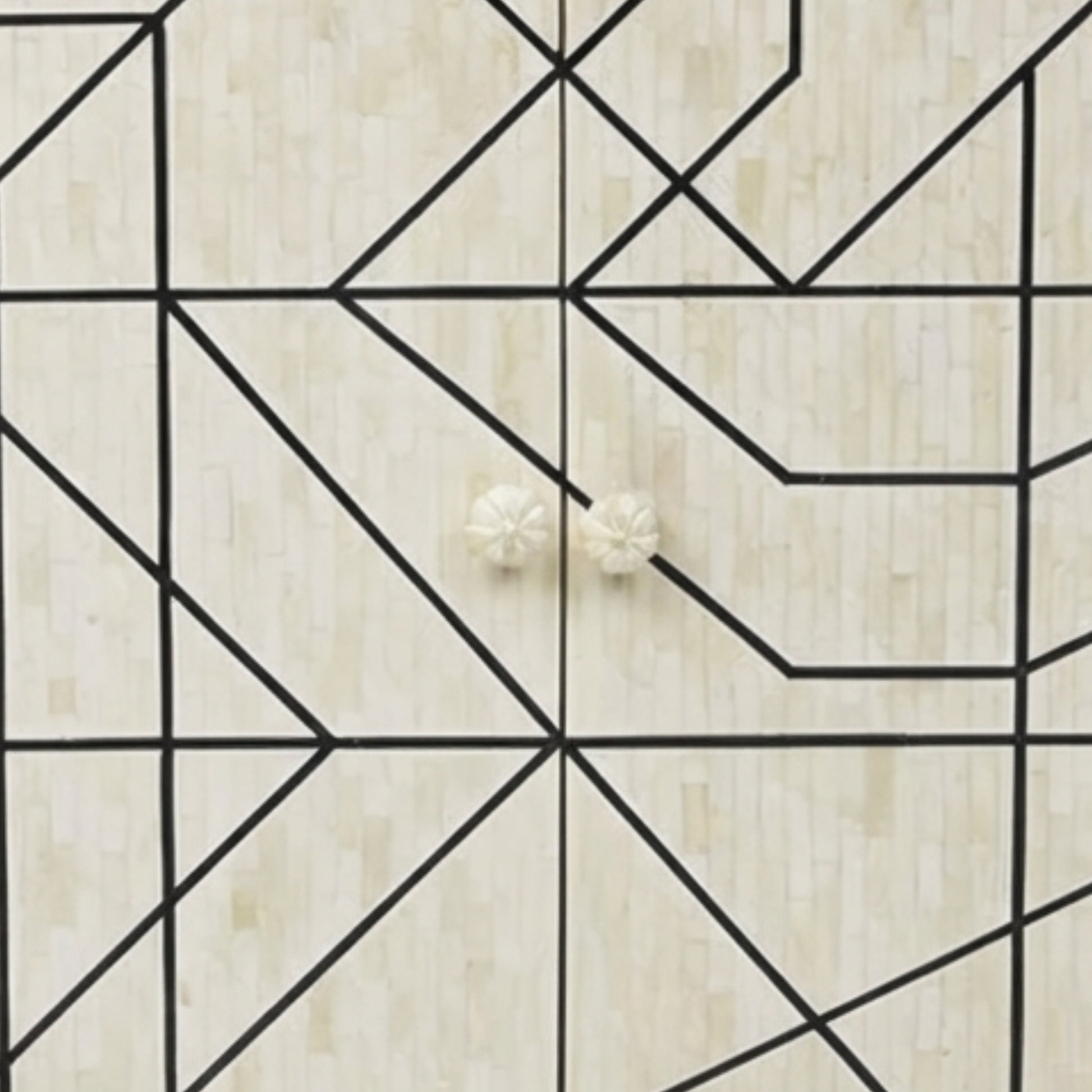 Two small round off-white flower-shaped stud earrings displayed on a light beige wood surface with a black geometric line pattern.