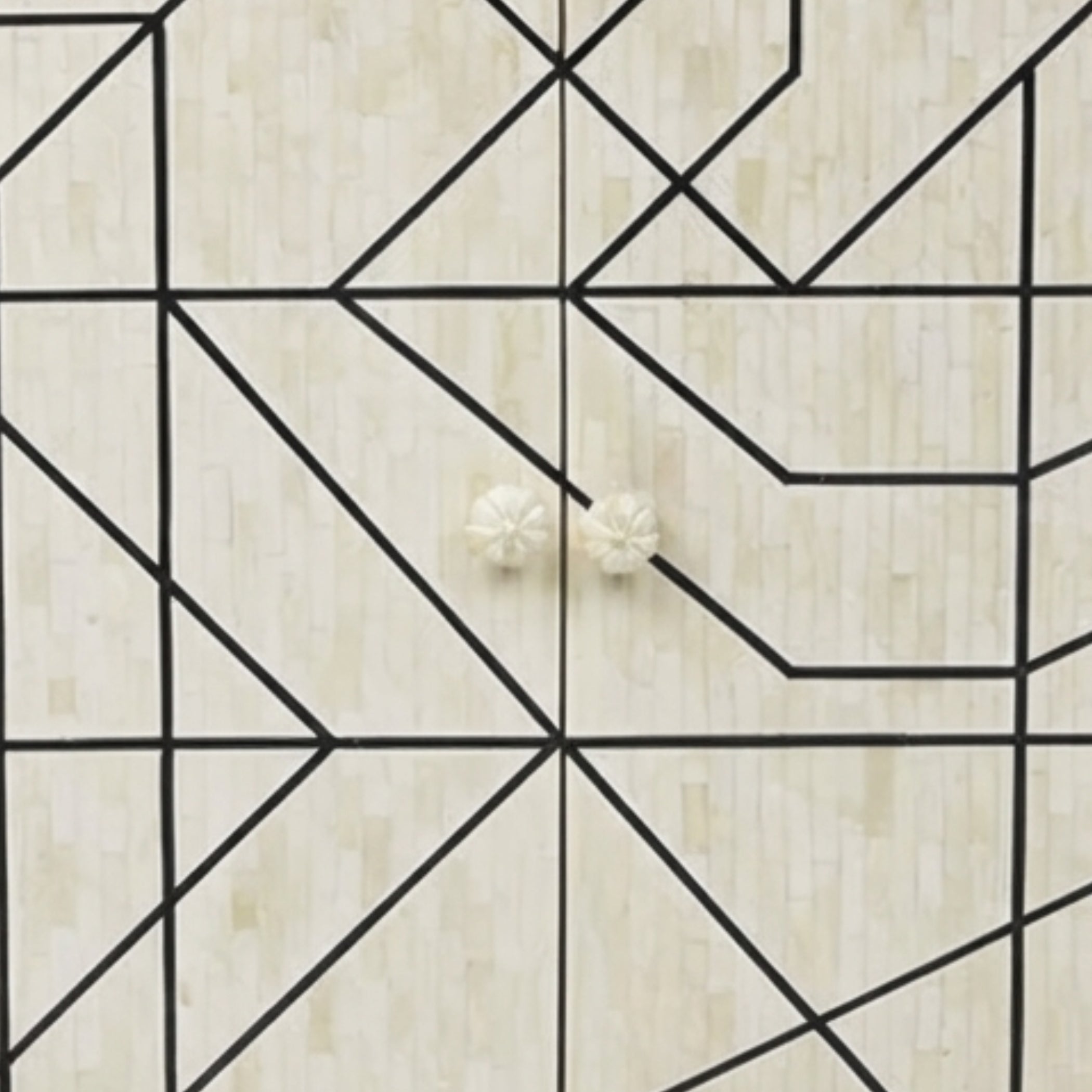 Two small round off-white flower-shaped stud earrings displayed on a light beige wood surface with a black geometric line pattern.