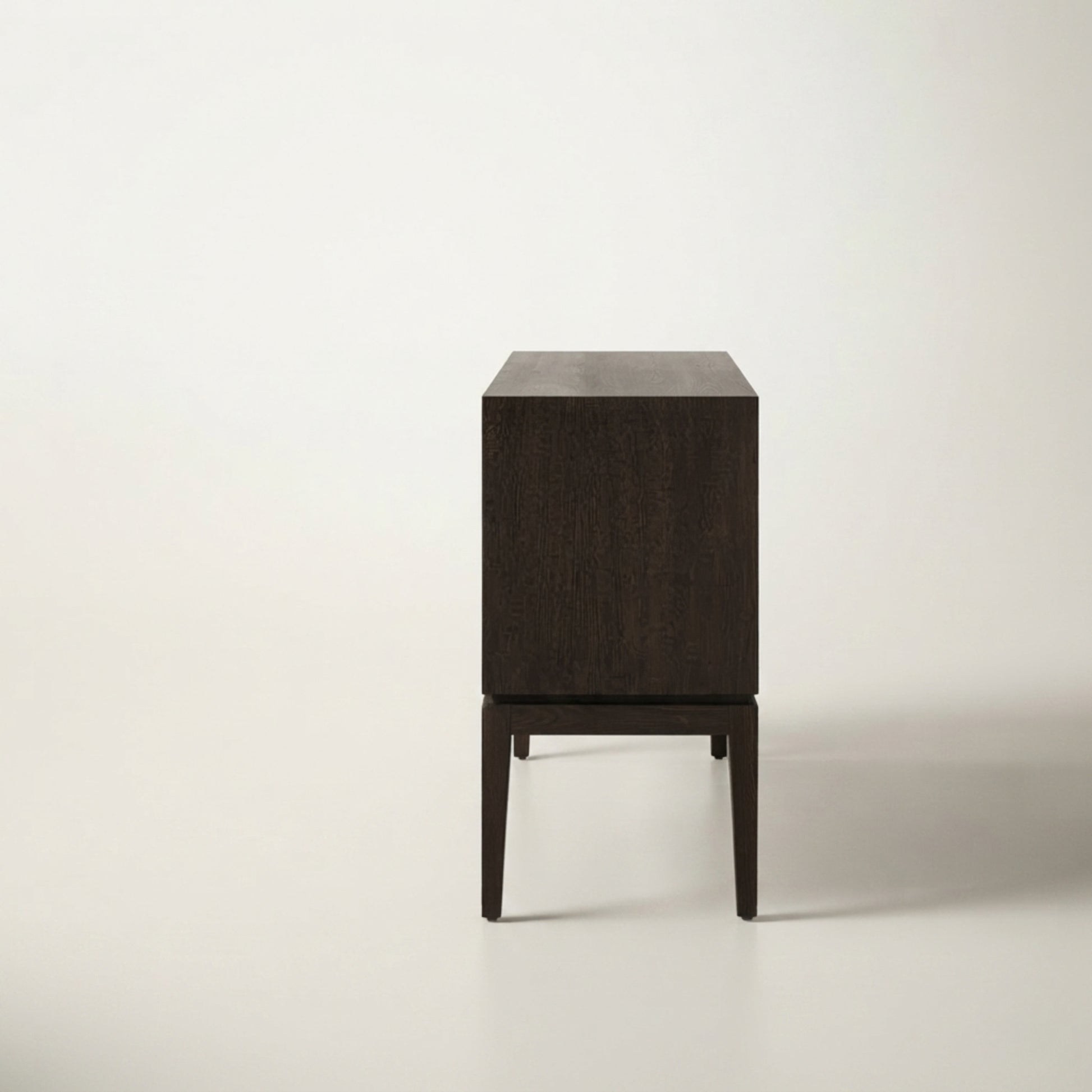 A modern dark brown wooden sideboard or cabinet with a minimalist block design and tapered legs, photographed against a clean off-white background.