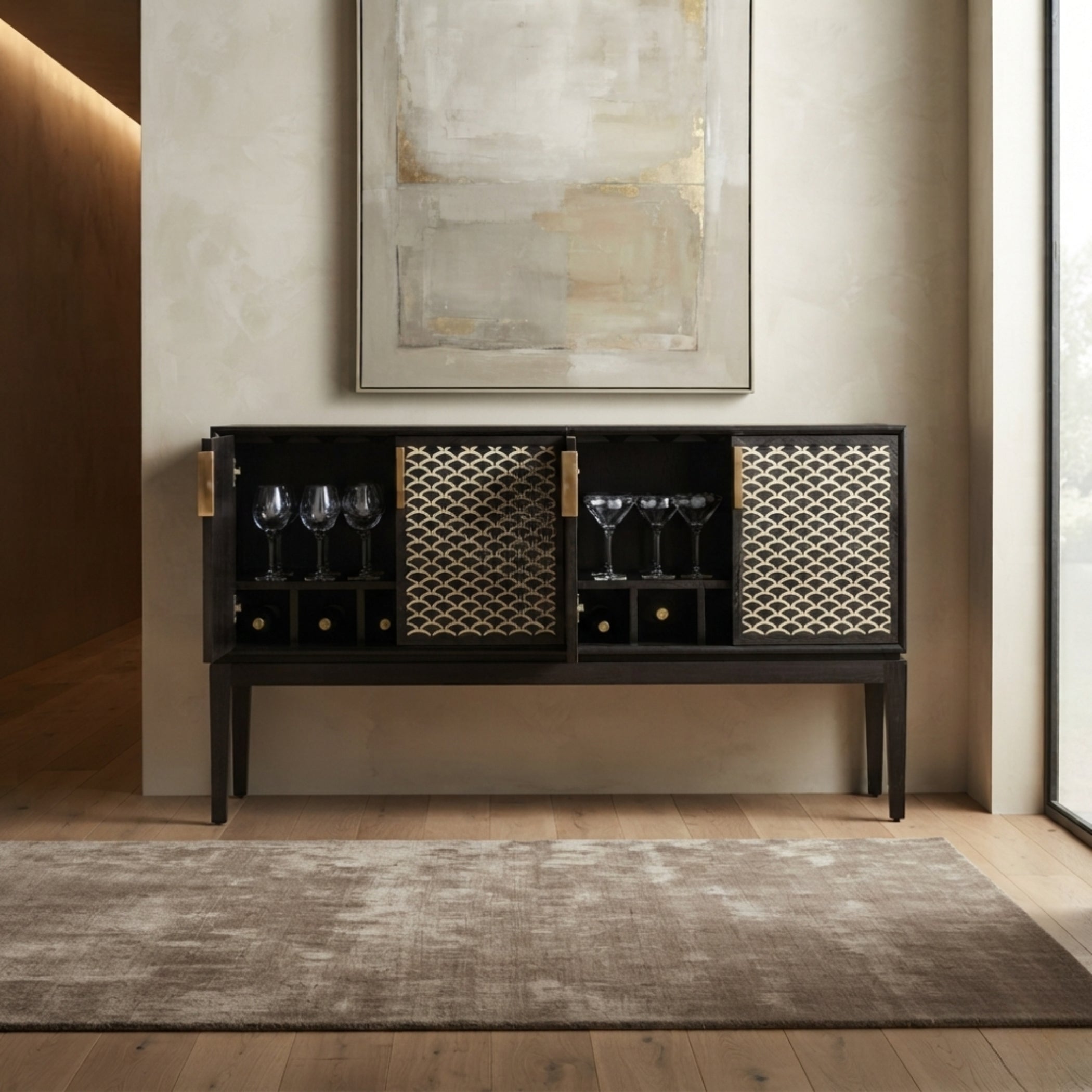 A modern black bar cart with gold geometric patterned doors and gold hardware, styled in a warm, minimalist interior with a textured rug and wall art.