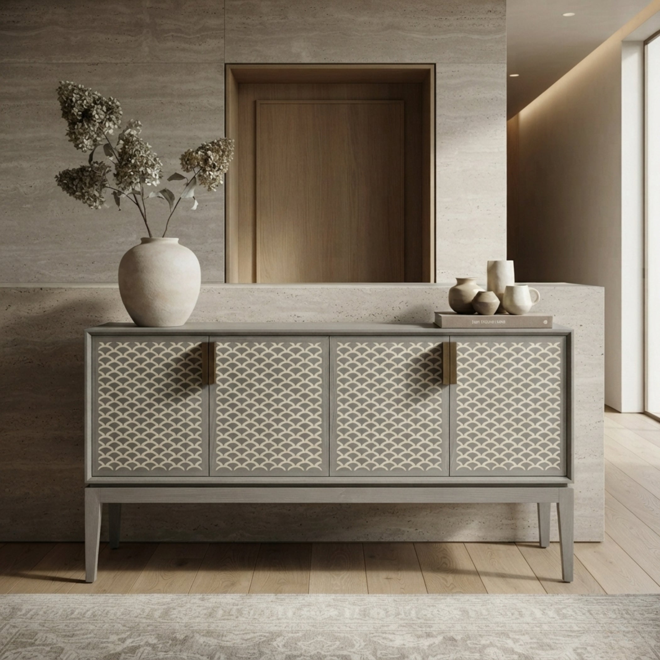 A modern sideboard cabinet with three patterned doors in a warm gray finish, styled in a minimalist entryway with a large ceramic vase and dried flowers on top.