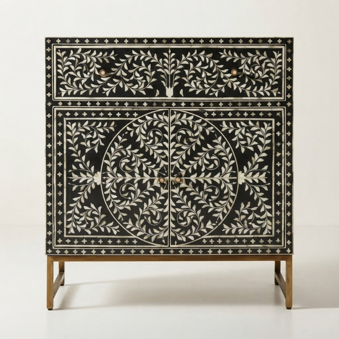 A black and white mother-of-pearl inlaid console cabinet with gold-toned legs, styled in a modern, elegant entryway with a framed abstract print and a small vase on top.