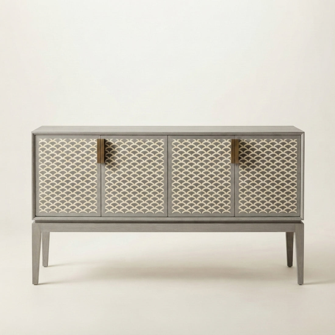 A modern sideboard cabinet with three patterned doors in a warm gray finish, styled in a minimalist entryway with a large ceramic vase and dried flowers on top.