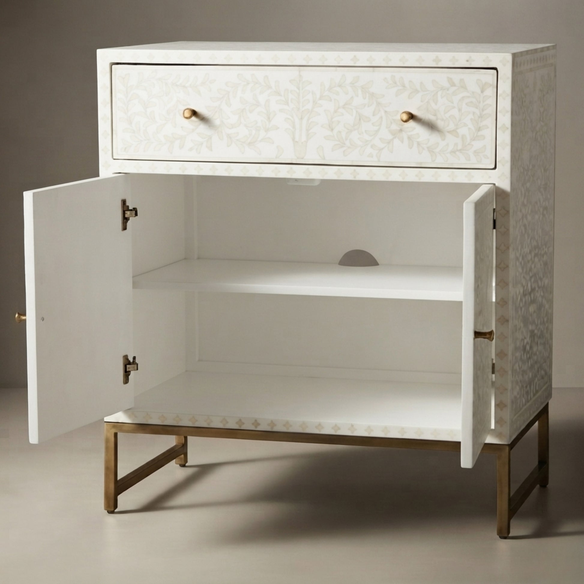 A white two-drawer nightstand with open double doors, featuring a gold-tone metal frame and legs, brass drawer pulls, and a subtle damask pattern on the drawer fronts and outer sides.
