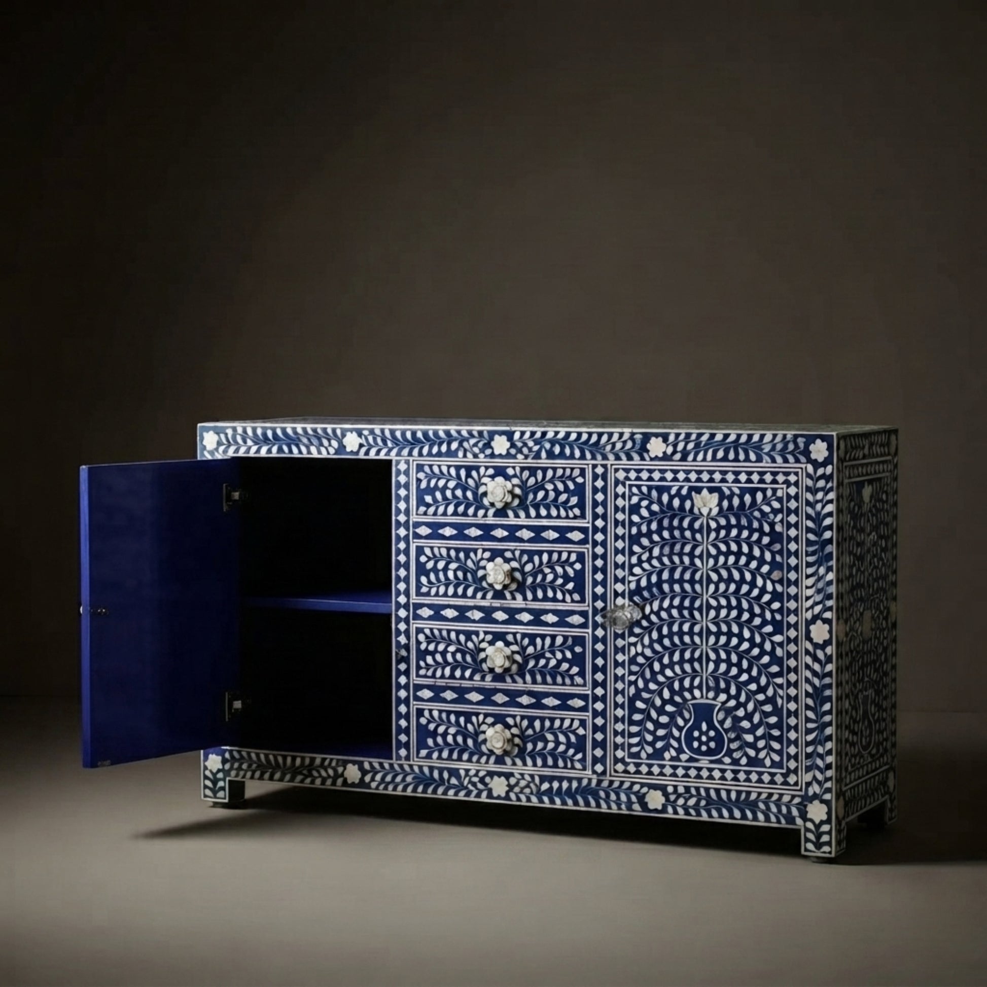 A blue and white bone-inset sideboard cabinet with one door open, showing a dark interior. The cabinet features intricate white bone patterns on a deep blue background and ornate silver-toned drawer pulls.