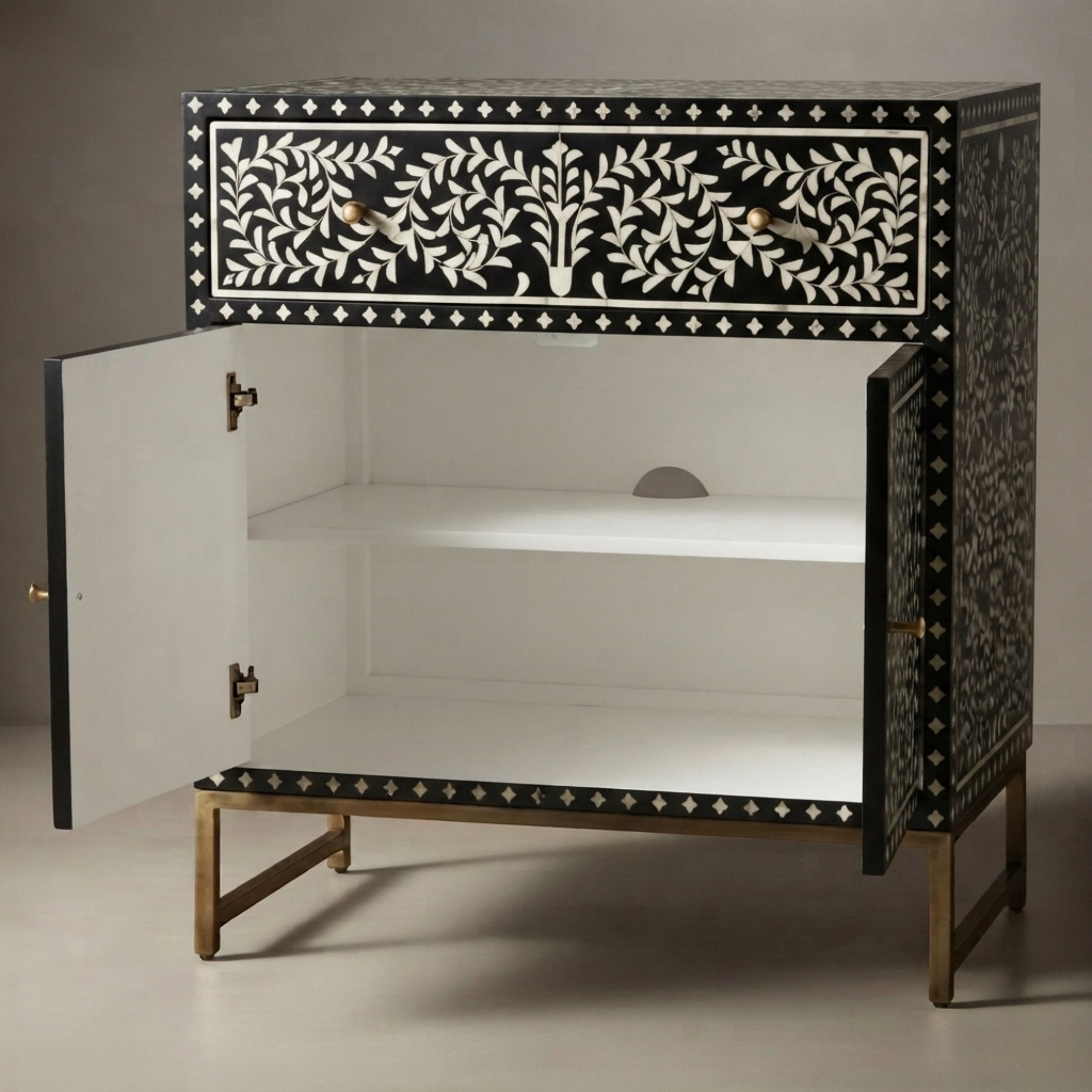 A black and white bone-inlay cabinet with gold metal legs, shown with its doors open to reveal a white interior and two shelves.