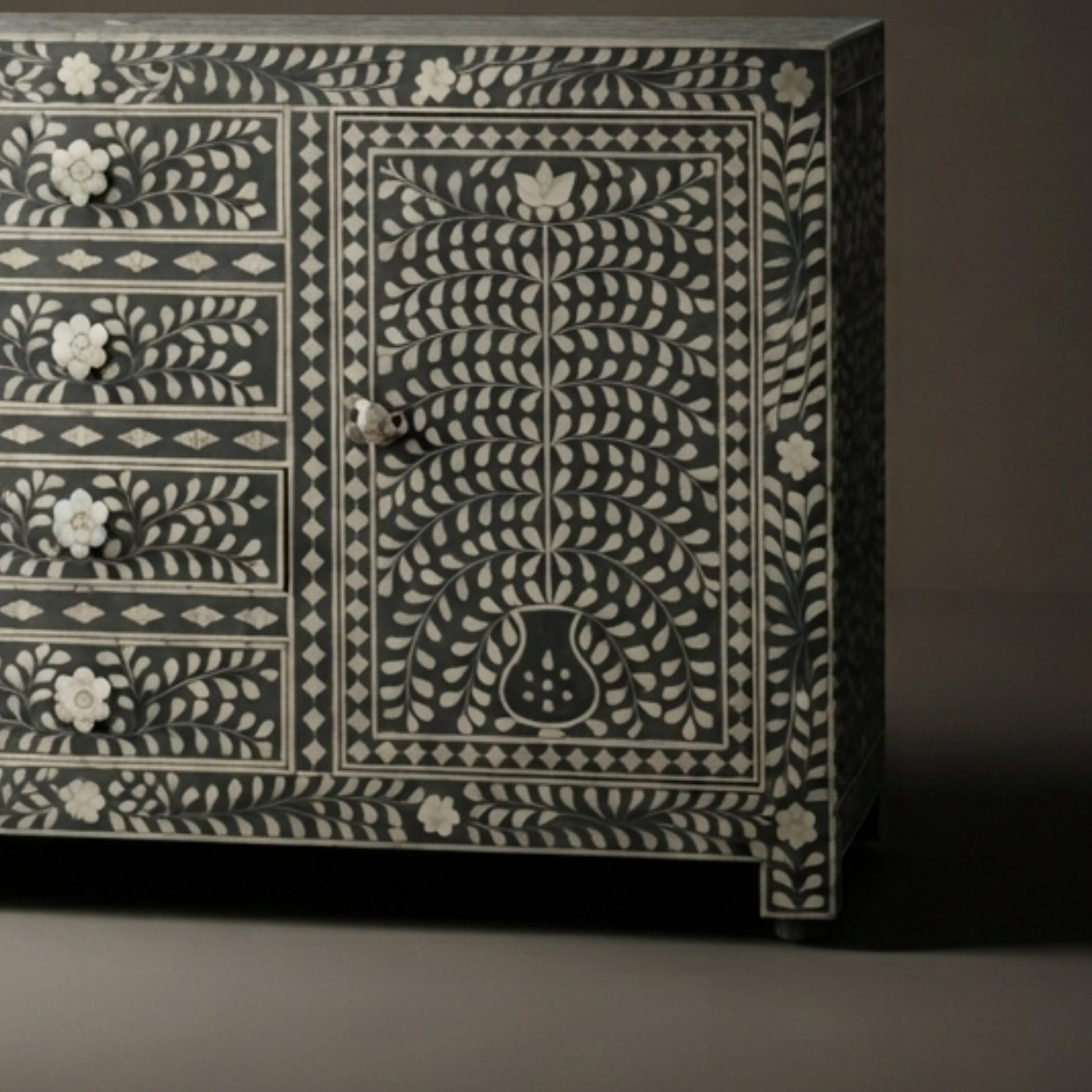 A dark wood sideboard or credenza with intricate white bone-inlay floral and geometric patterns, featuring five drawers on the left and a larger door on the right.