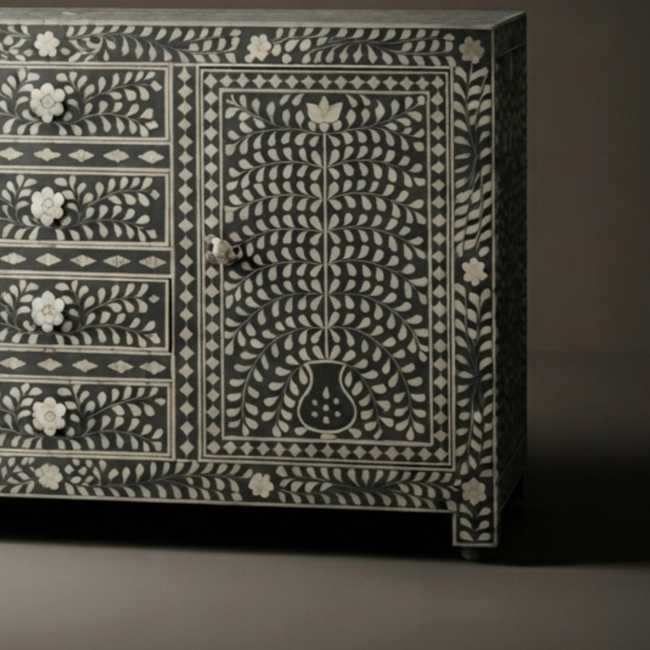 A dark wood sideboard or credenza with intricate white bone-inlay floral and geometric patterns, featuring five drawers on the left and a larger door on the right.