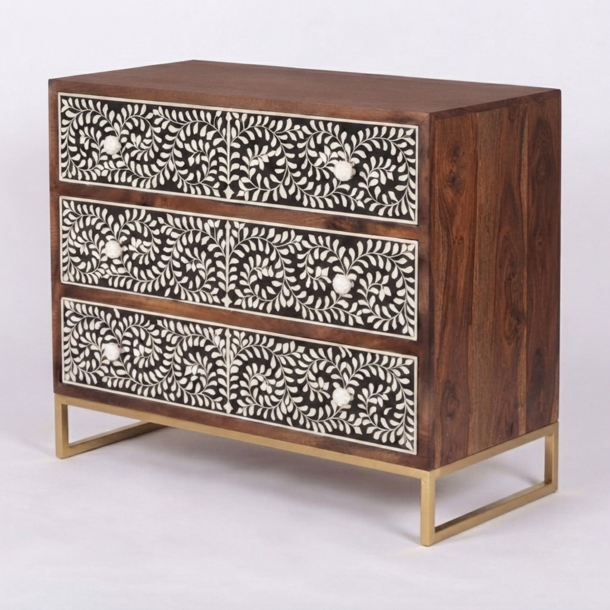 A three-drawer wooden chest of drawers with intricate white bone-inlay floral patterns on the drawer fronts and a gold metal frame base, shown on a light gray background.