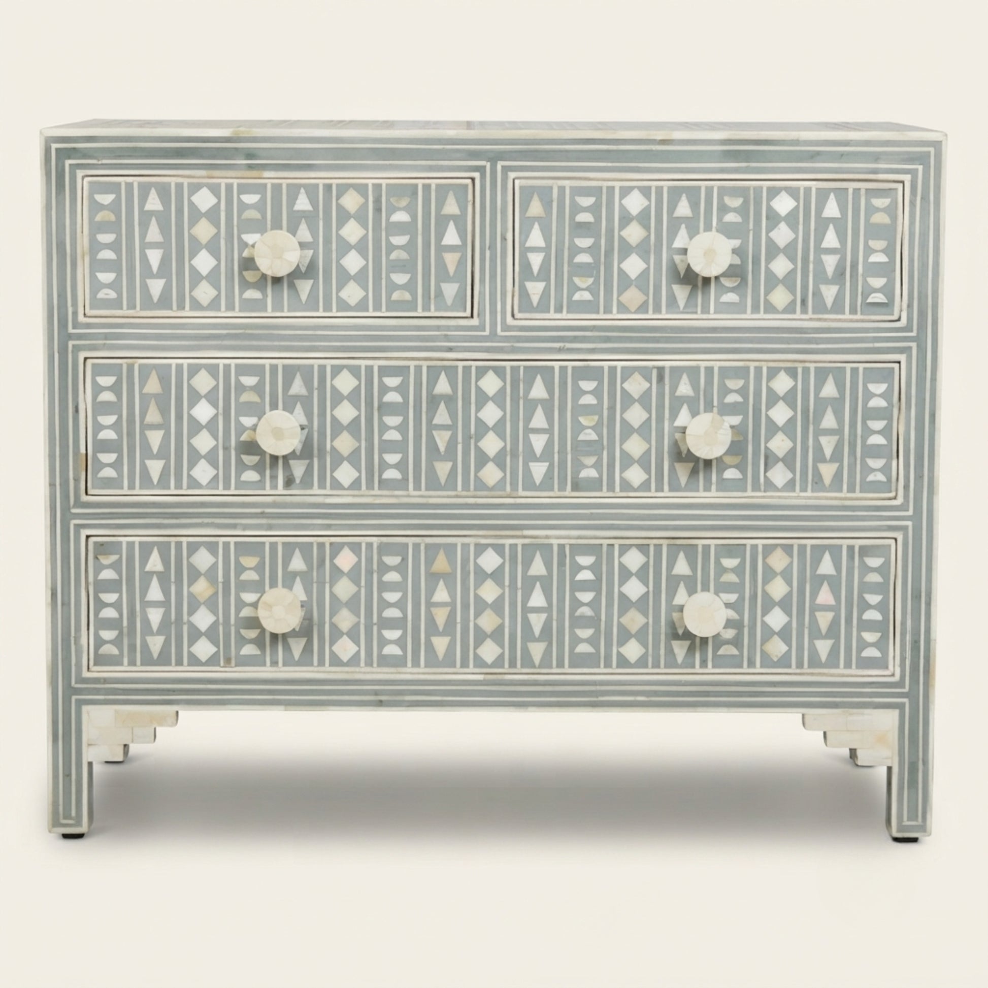 A three-drawer chest of drawers featuring intricate mother-of-pearl bone inlay geometric patterns in white and gray on a distressed sage green painted wood, with round white knobs.