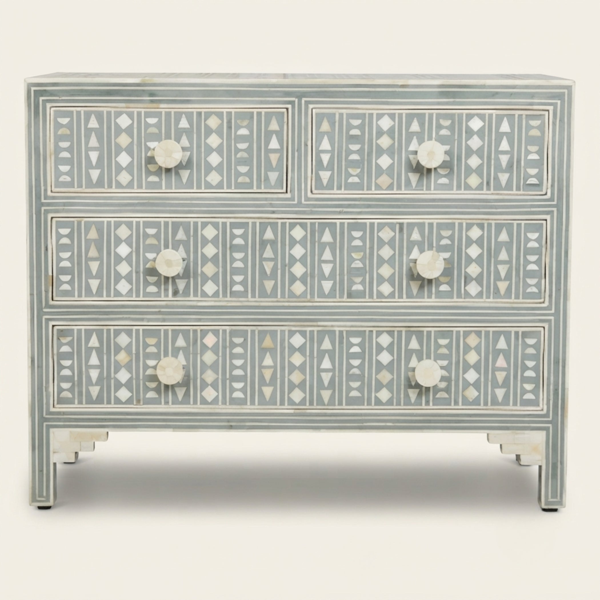 A three-drawer chest of drawers featuring intricate mother-of-pearl bone inlay geometric patterns in white and gray on a distressed sage green painted wood, with round white knobs.