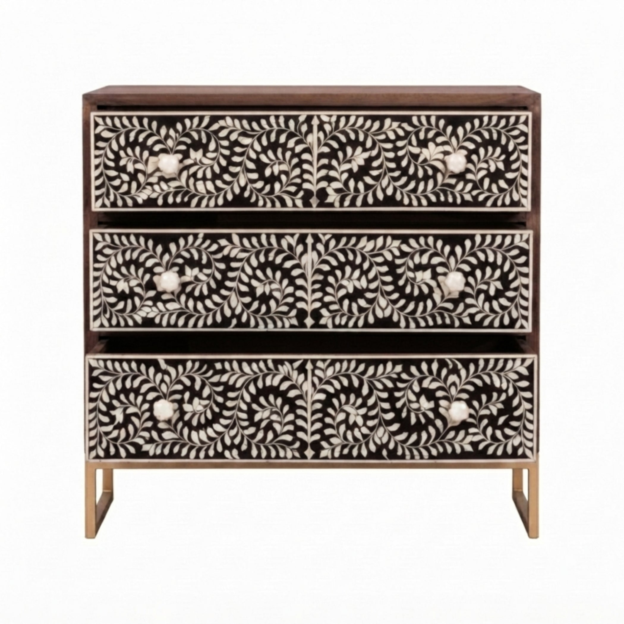 A three-drawer chest of drawers with a dark brown wood frame and intricate bone-inlay drawer fronts featuring a black and white floral and leaf pattern, supported by gold-toned legs.