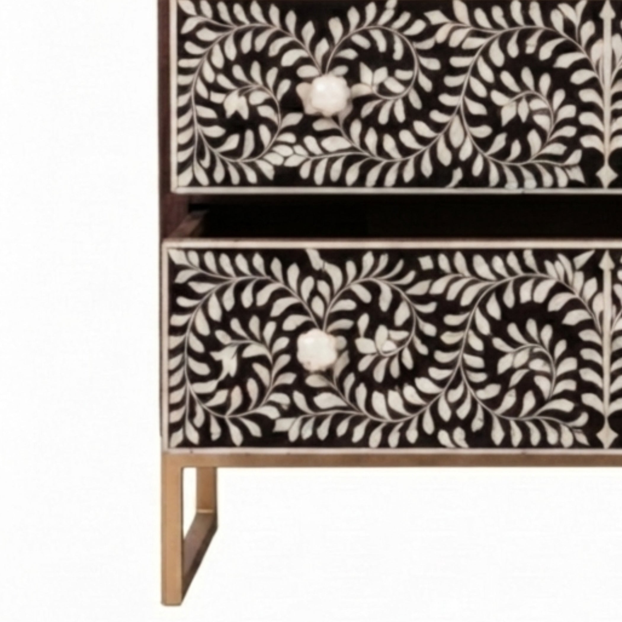 A close-up of a two-drawer chest or cabinet with black and white floral bone-inlay panels and small metallic legs, shown against a plain white background.