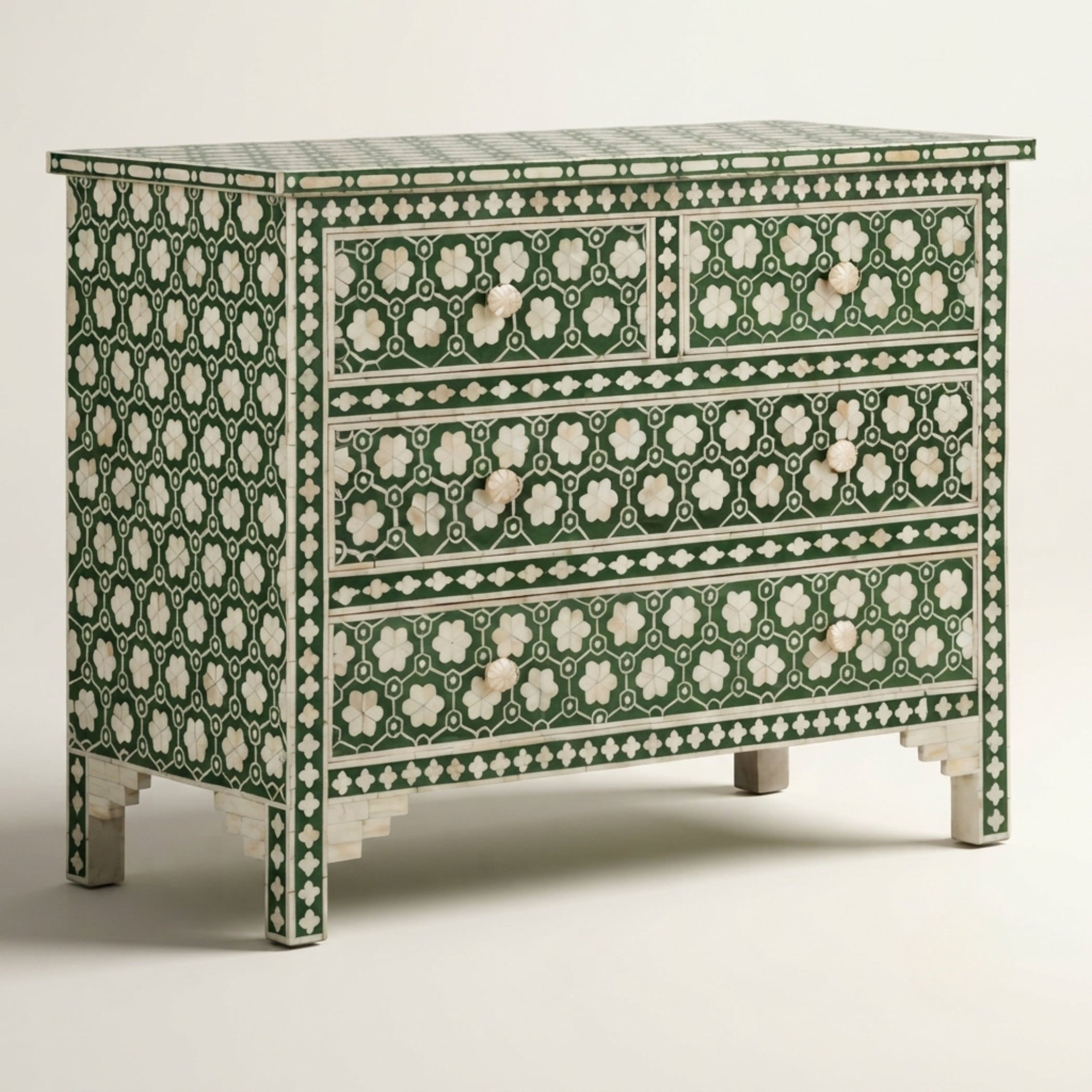An ornate three-drawer chest of drawers decorated with intricate green and white mother-of-pearl inlay patterns, shown against a neutral light gray background.