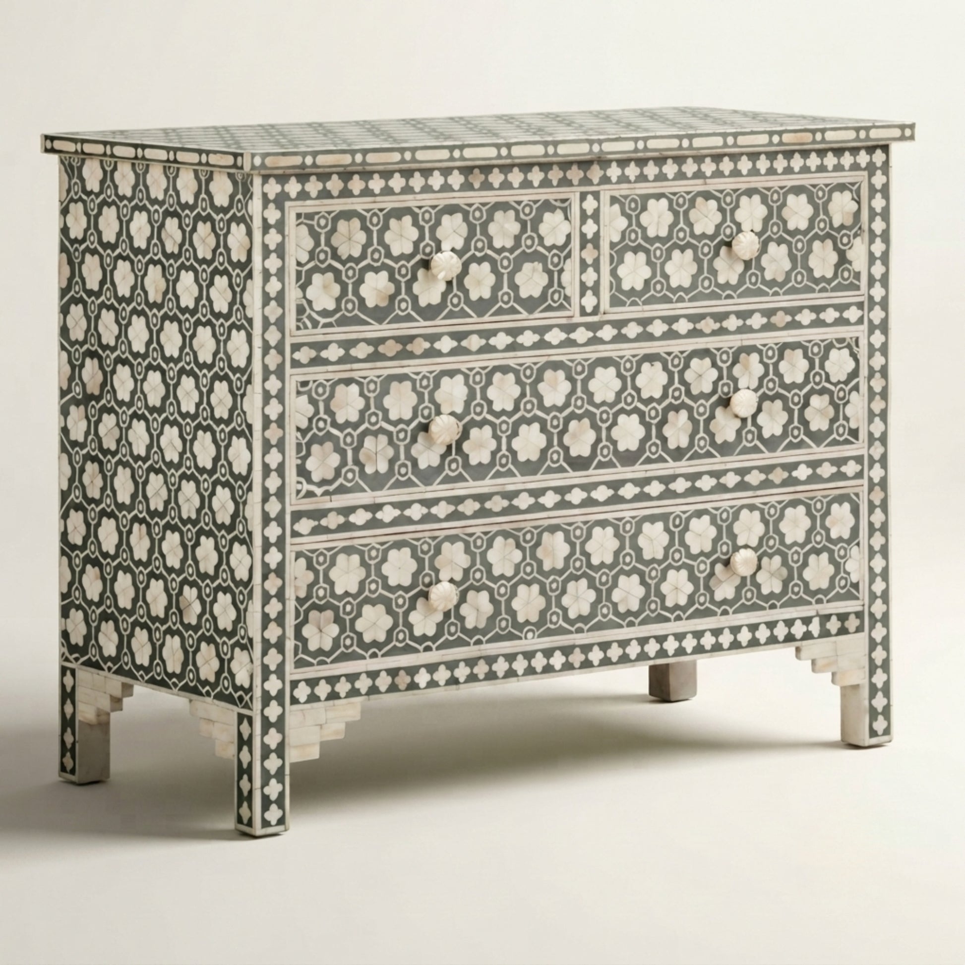 A three-drawer chest of drawers featuring an intricate black and white bone-inlay geometric pattern, photographed against a neutral light gray background.