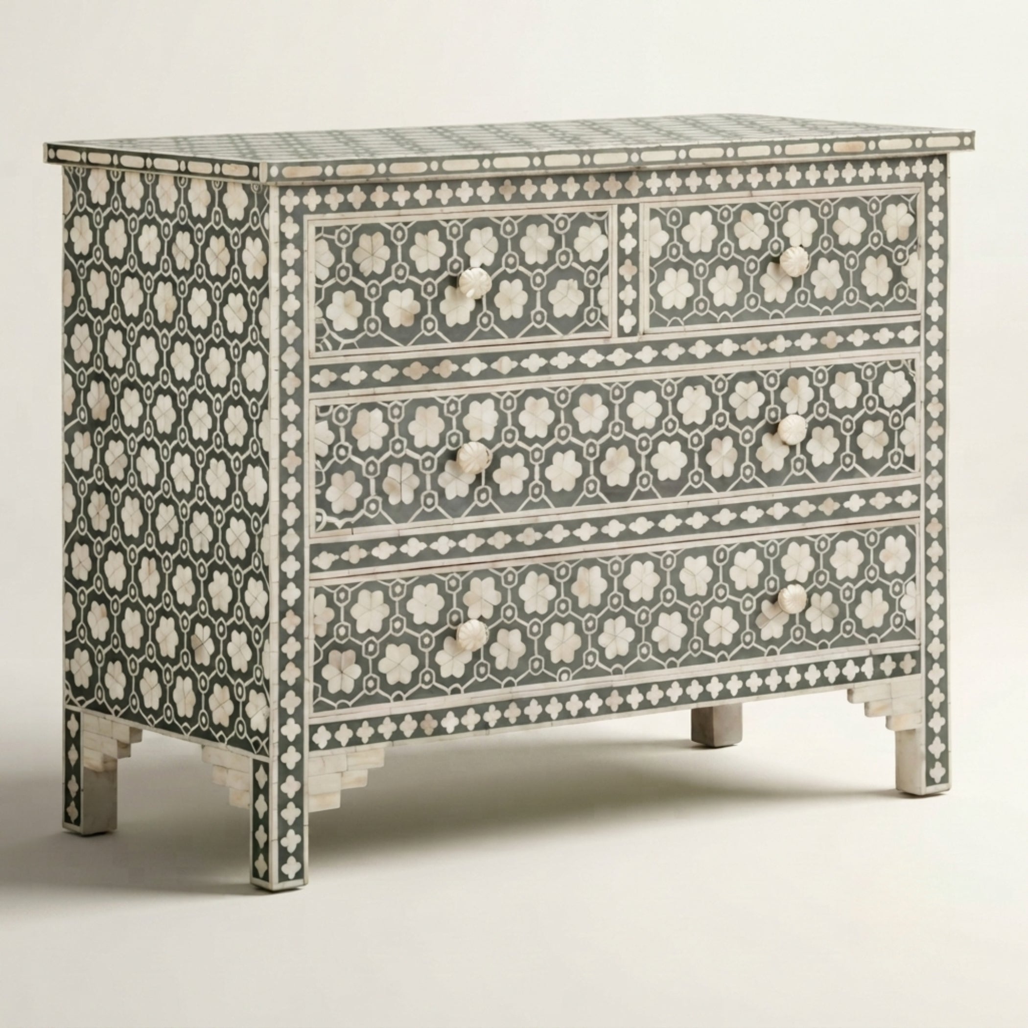 A three-drawer chest of drawers featuring an intricate black and white bone-inlay geometric pattern, photographed against a neutral light gray background.