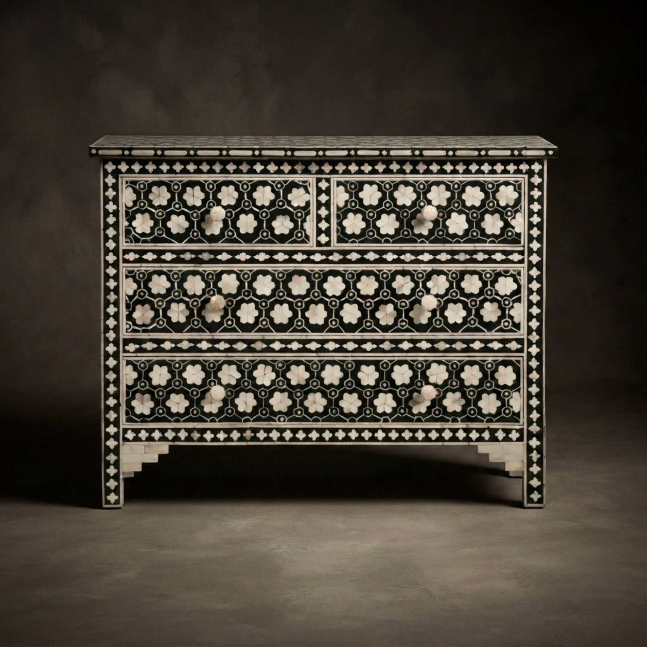 A three-drawer chest of drawers featuring intricate black and white bone-inlay geometric and floral patterns, set against a dark studio background.
