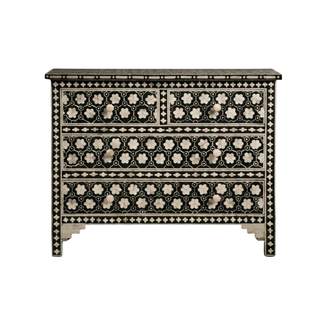 A black and white mother-of-pearl inlaid chest of drawers stands in a styled room next to a beige armchair, with a dark ceramic vase holding dried branches on top.