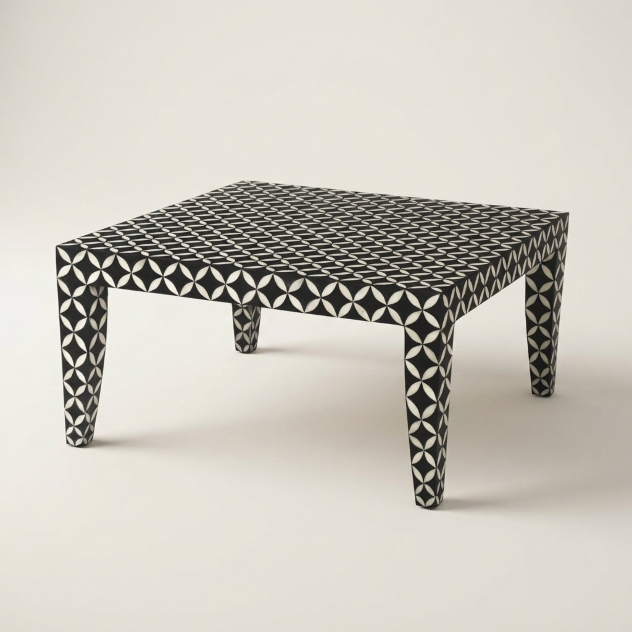 A square coffee table with a black and white geometric bone-inlay pattern, photographed on a neutral light beige background.