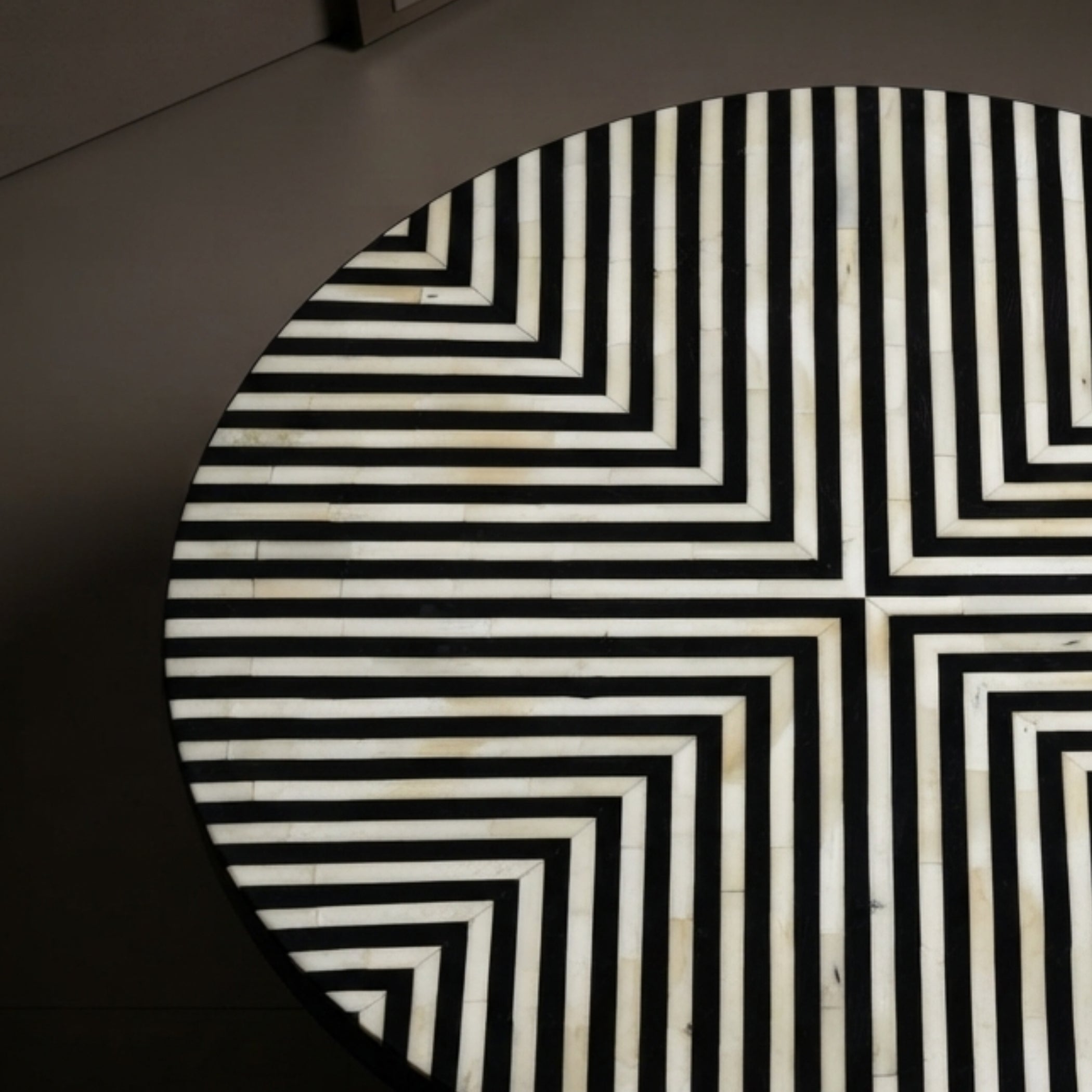A close-up of a round table featuring a black and white geometric inlay pattern made of concentric rectangular lines.