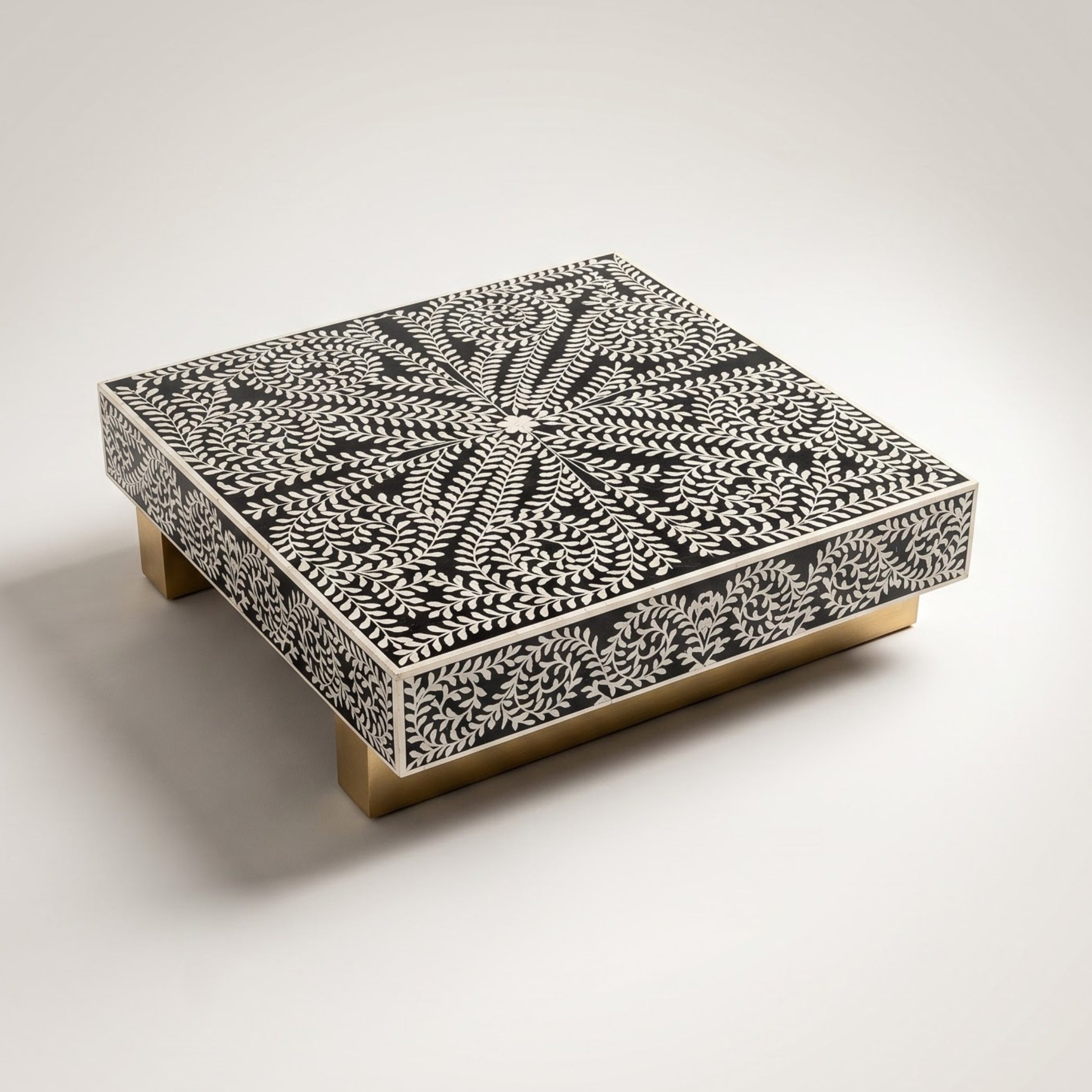 A square decorative box with a black and white bone-insect pattern on the lid and sides, supported by four gold-toned legs, photographed on a light gray studio background.