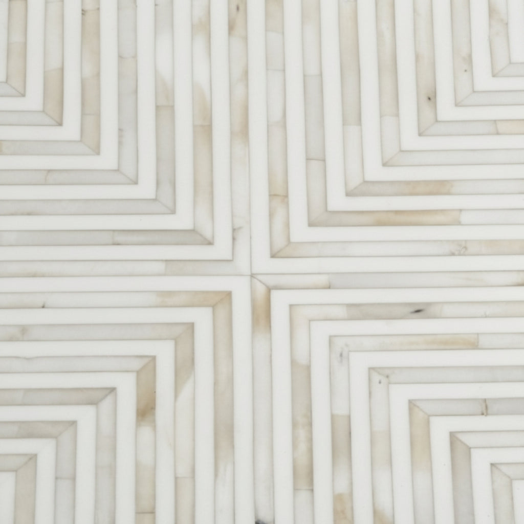 A close-up of a geometric mosaic tile pattern featuring concentric square frames in warm off-white and beige marble or stone.