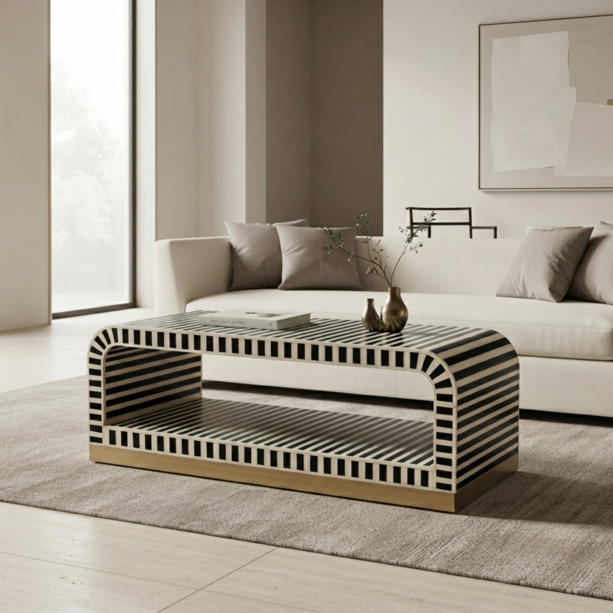 A modern rectangular coffee table with a black and white striped pattern and a gold-toned base, styled in a minimalist living room next to a white sofa.
