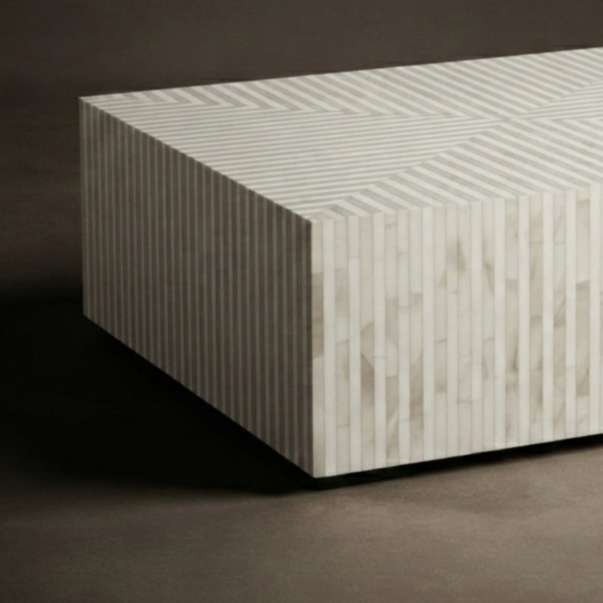 A modern rectangular side table or coffee table with a geometric striped pattern in light beige and white, set against a dark brown background.