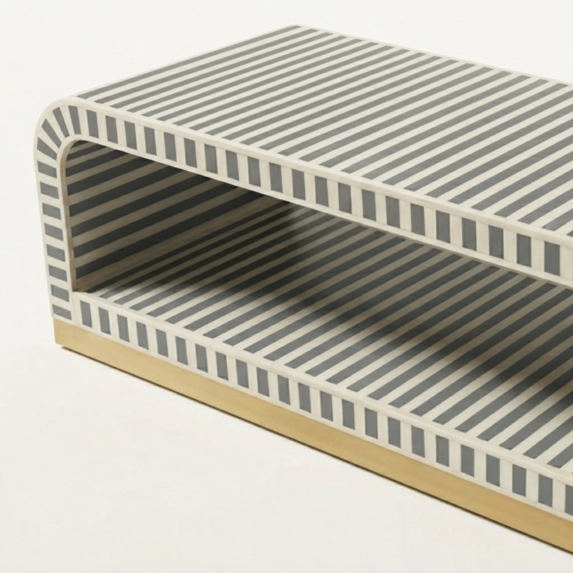 A modern low coffee table with a geometric striped pattern in gray and off-white, featuring a light wood base.