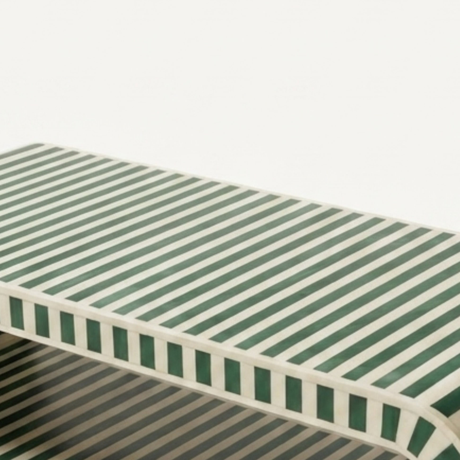 A low rectangular bench with a green and off-white striped pattern on the seat and sides, shown against a plain white background.