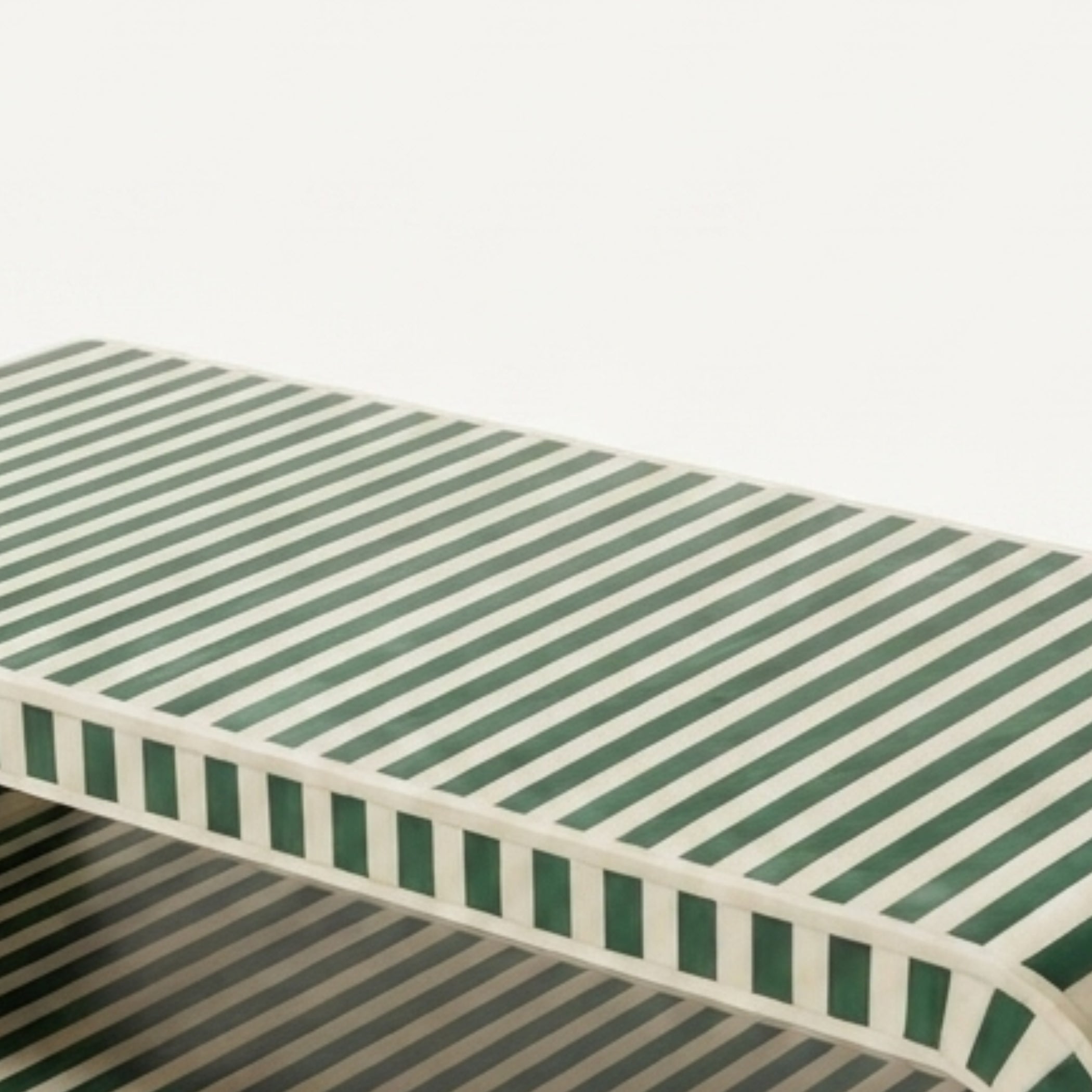 A low rectangular bench with a green and off-white striped pattern on the seat and sides, shown against a plain white background.