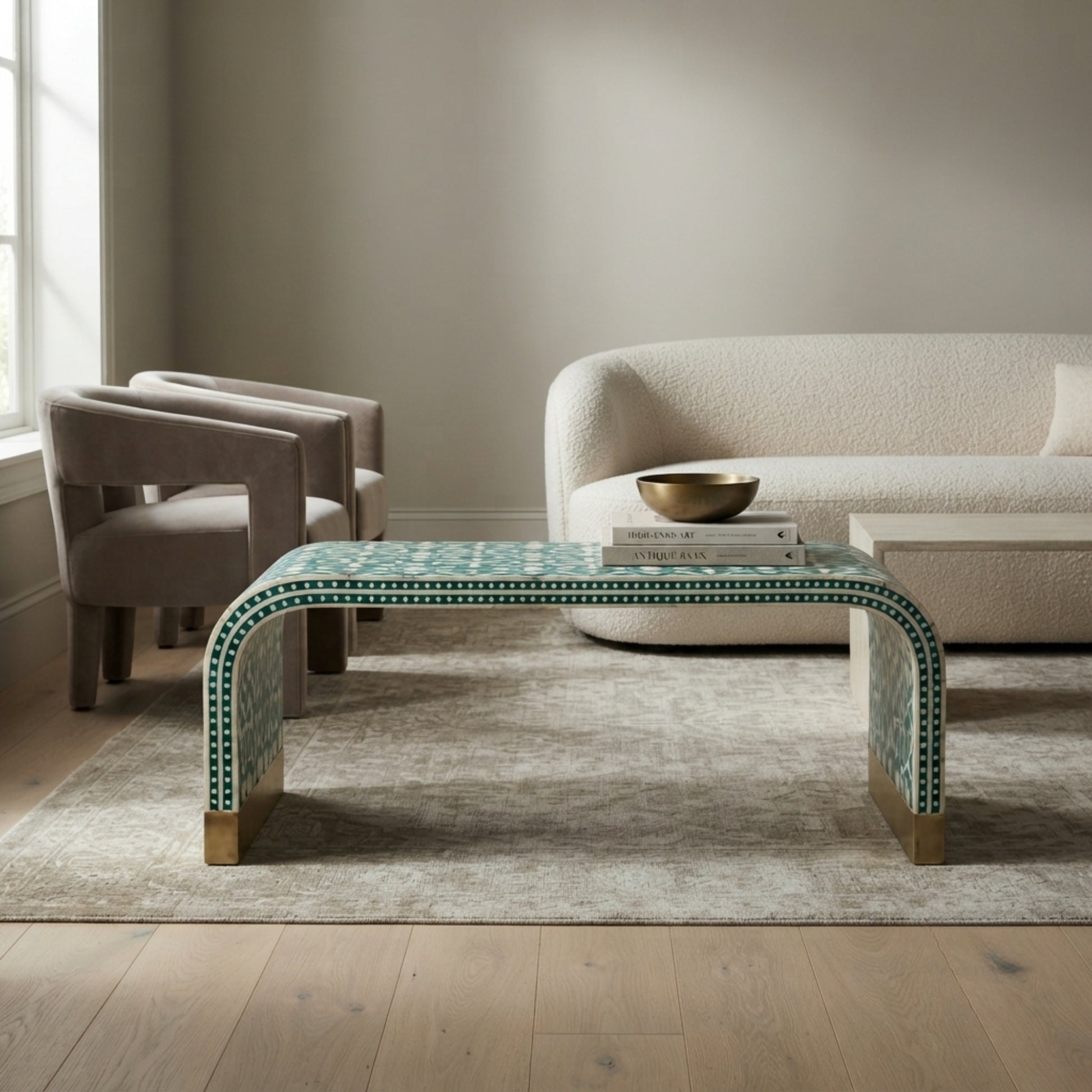 A modern curved coffee table with a green and white geometric mosaic tile pattern and gold-toned legs, styled in a contemporary living room setting.