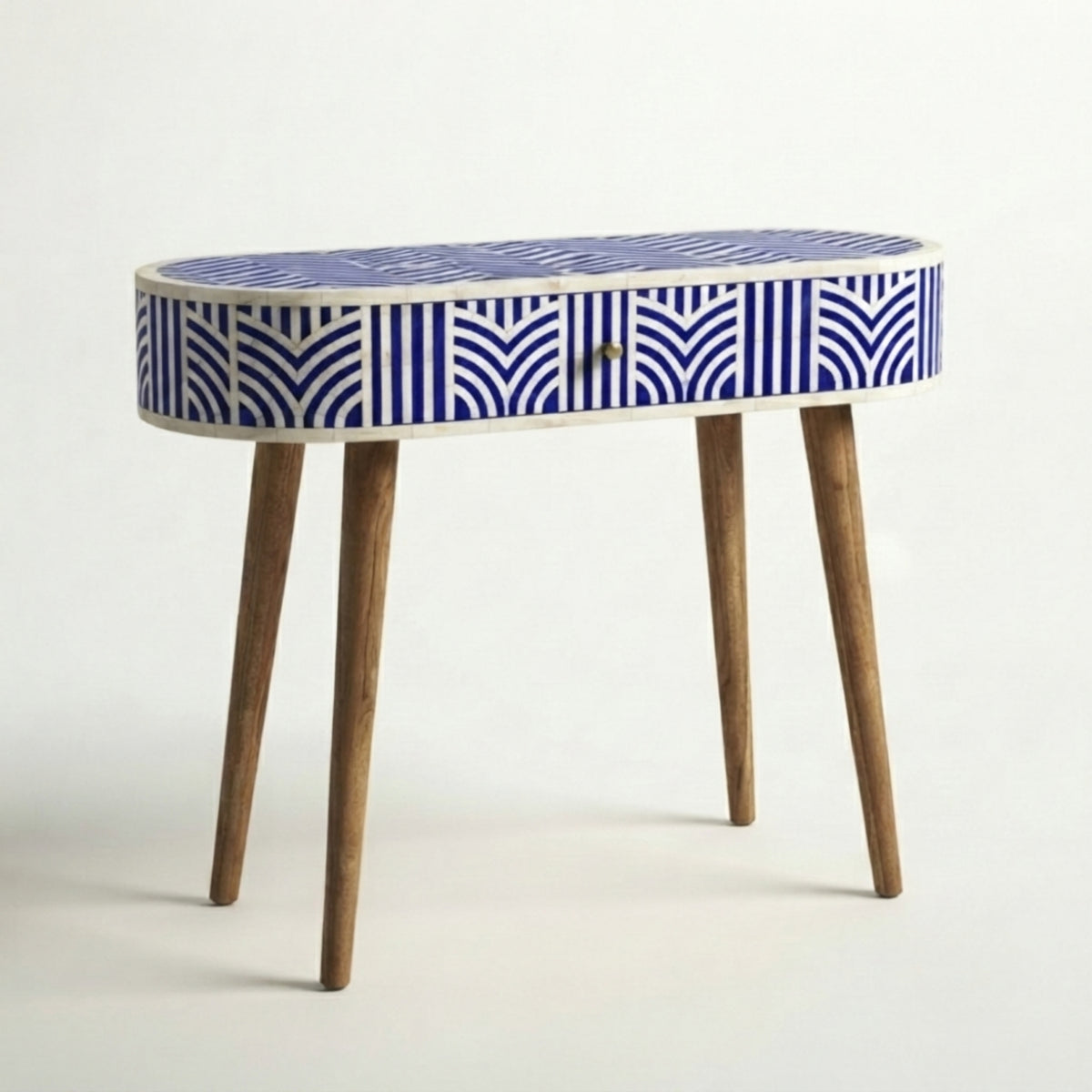 An oval console table with a blue and white geometric patterned bone-in-laminate top, a single drawer, and four tapered wooden legs, shown against a plain white studio background.