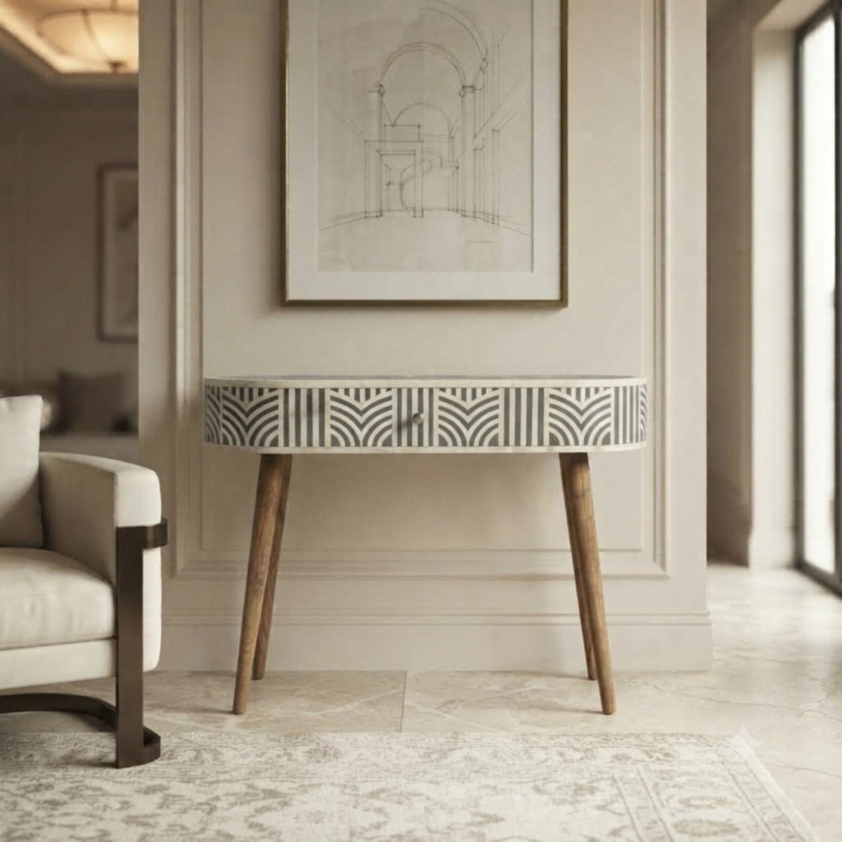 A modern console table with a white and gray geometric patterned front and natural wood legs, styled in a bright, elegant interior next to a white armchair.