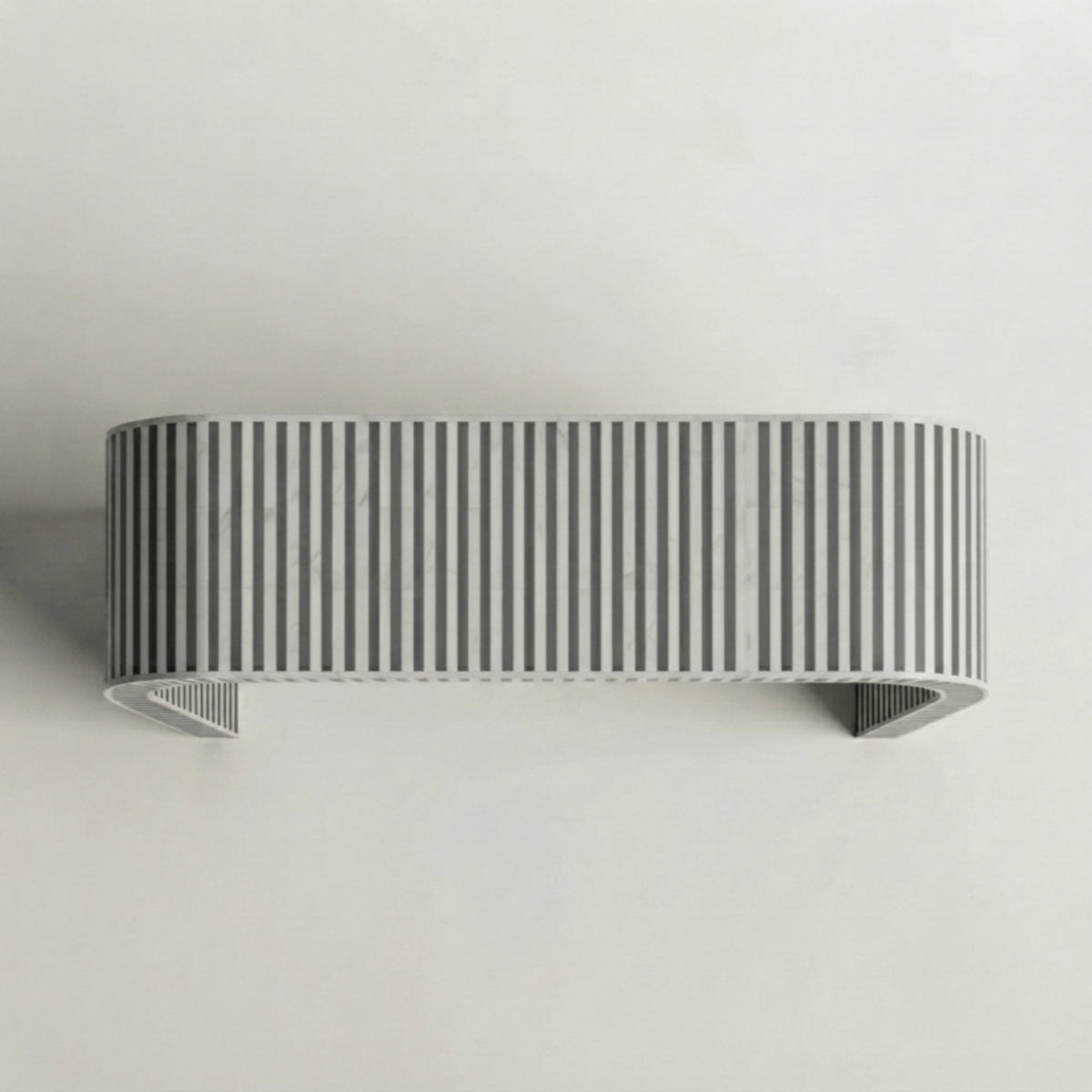 A modern wall-mounted rectangular shelf with a curved top and bottom, featuring a vertical striped pattern in gray and white, mounted on a plain light gray wall.