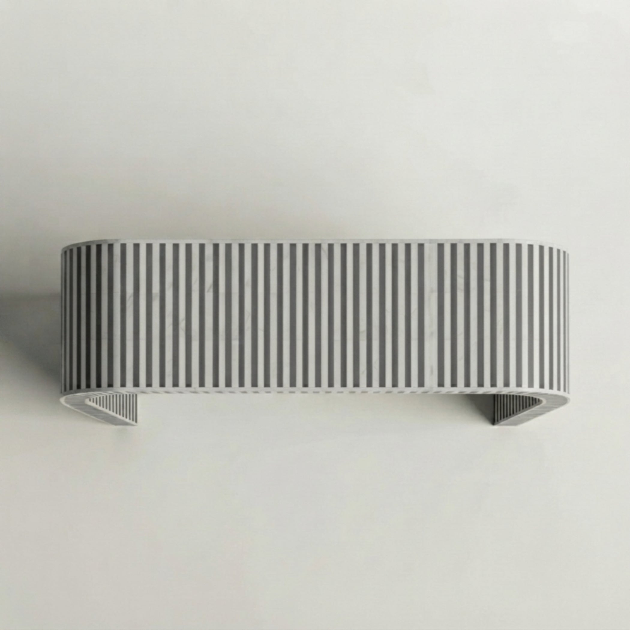 A modern wall-mounted rectangular shelf with a curved top and bottom, featuring a vertical striped pattern in gray and white, mounted on a plain light gray wall.