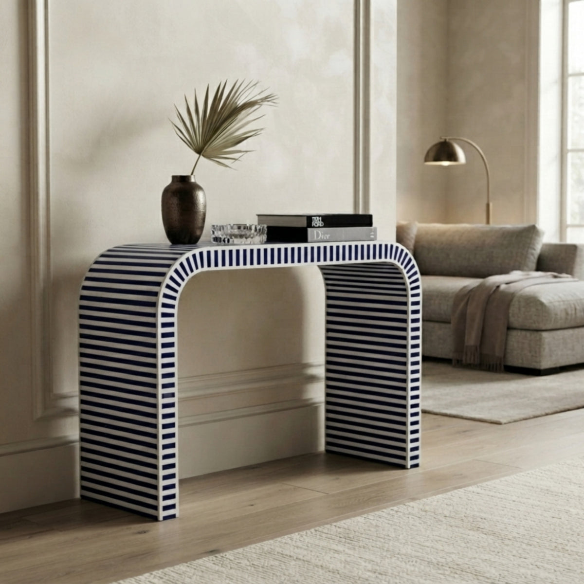 A modern console table with a bold blue and white striped pattern, styled in a neutral-toned living room setting.