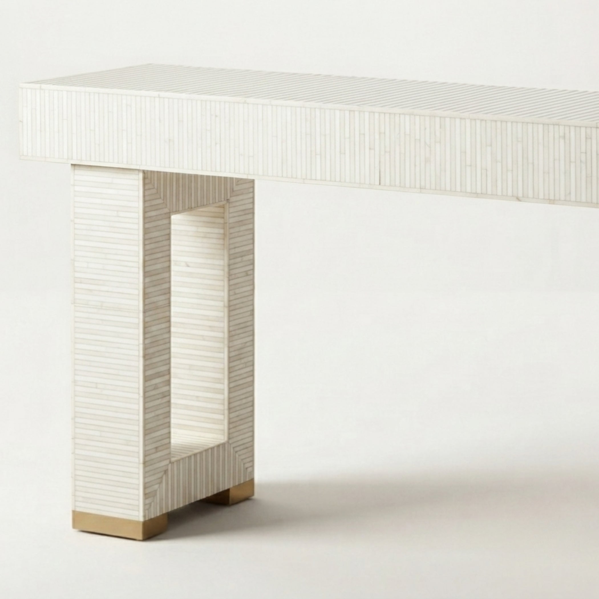 A modern console table featuring a rectangular top and a sculptural, open rectangular pedestal base, both crafted from a textured, vertically ribbed off-white material with light wood feet.