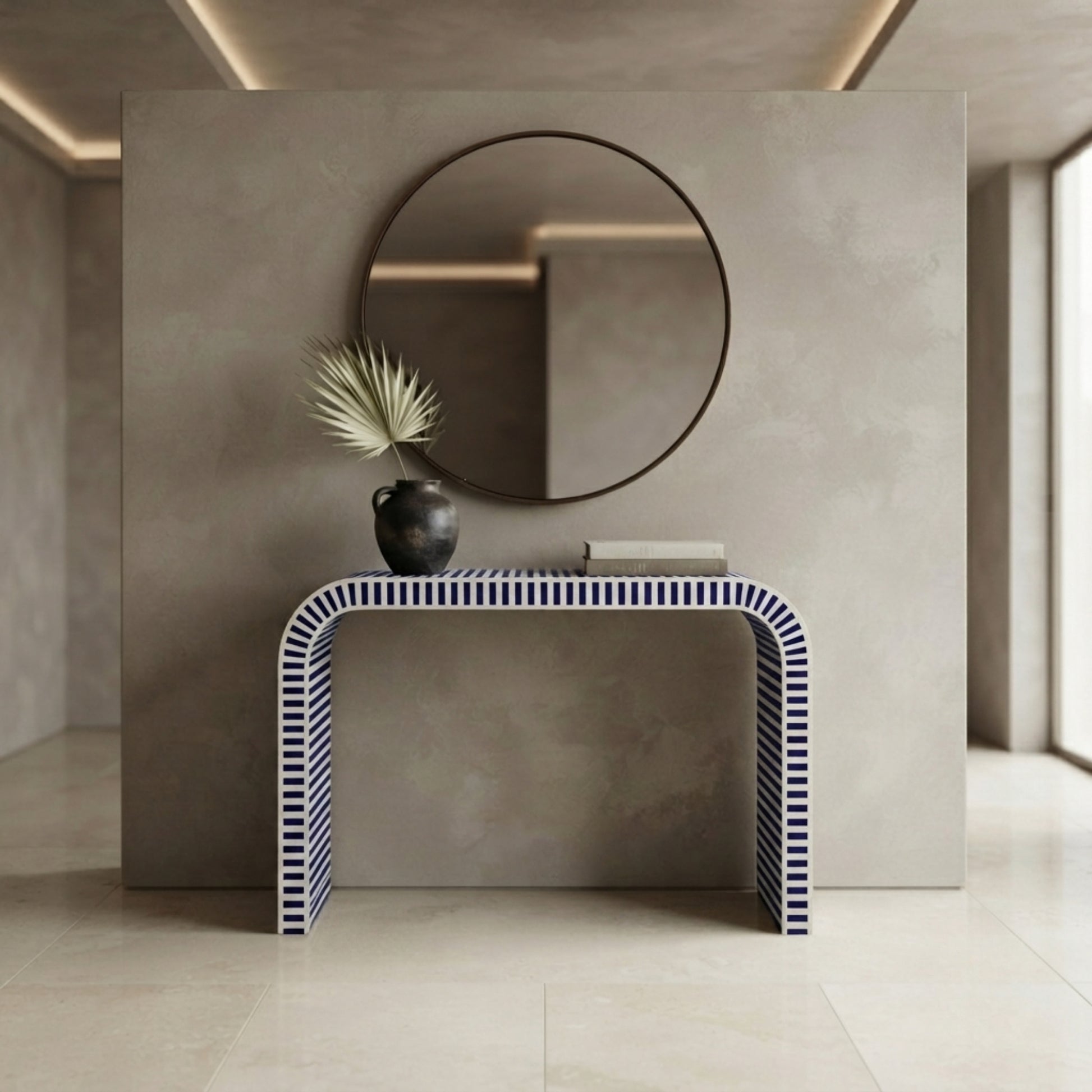 A modern console table with a curved U-shape design, featuring a navy and white striped pattern on the front and sides, styled in a minimalist interior setting with a round mirror and a small vase on top.