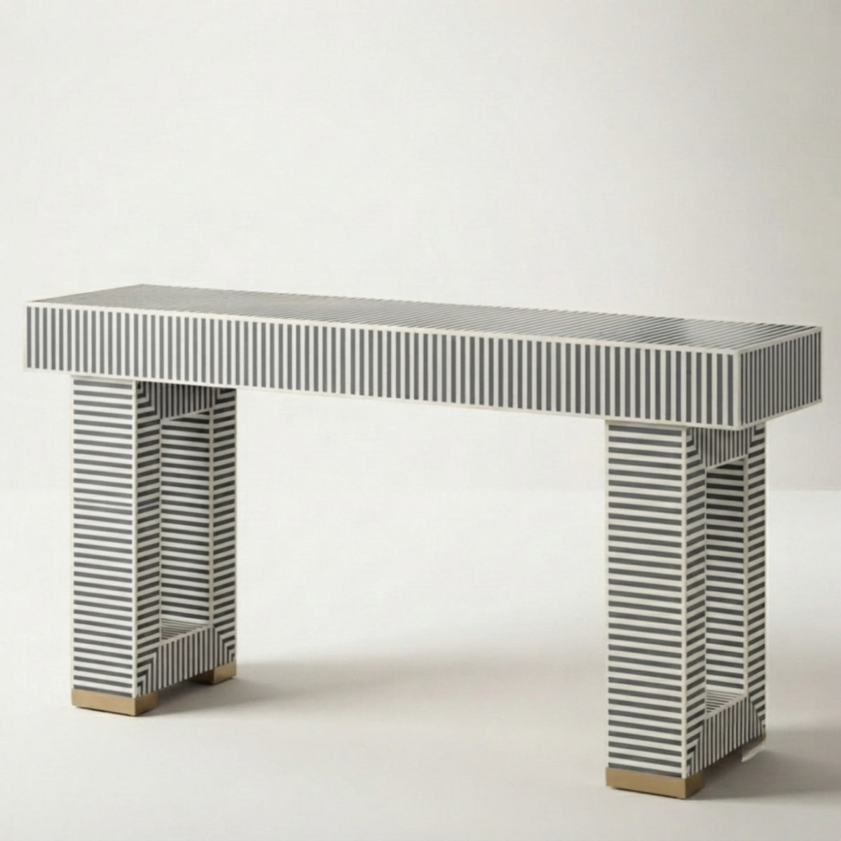 A modern console table with a rectangular top and two matching legs, both covered in narrow black and white striped bone inlay, finished with small gold-toned wooden feet.