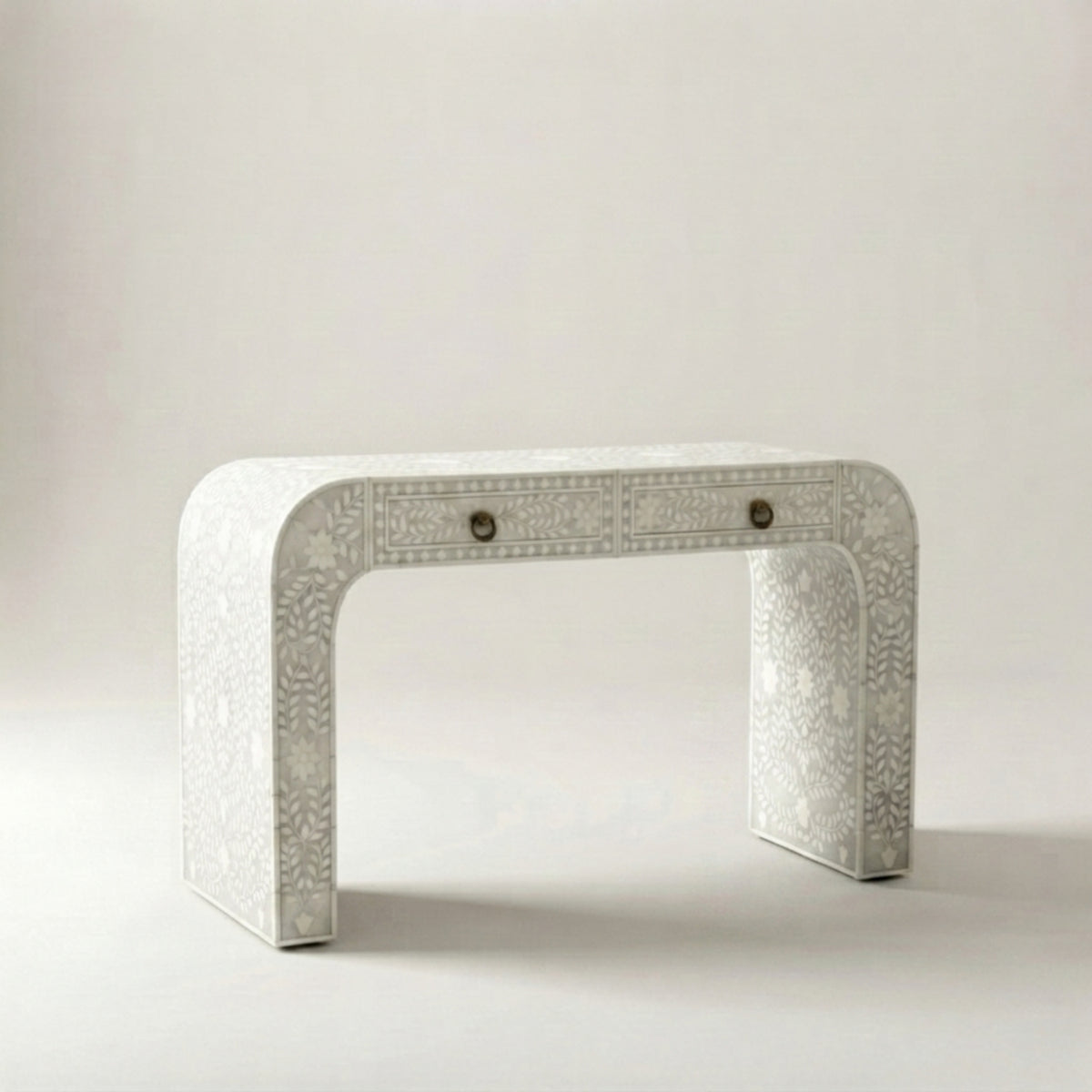 A white carved console table with two drawers and small round metal knobs, set against a neutral light gray background.