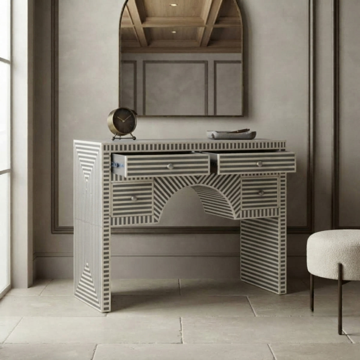 A modern bone-style vanity table with striped bone inlays in gray and white, featuring drawers, an arched center detail, and a matching wall mirror above it in a styled interior room.