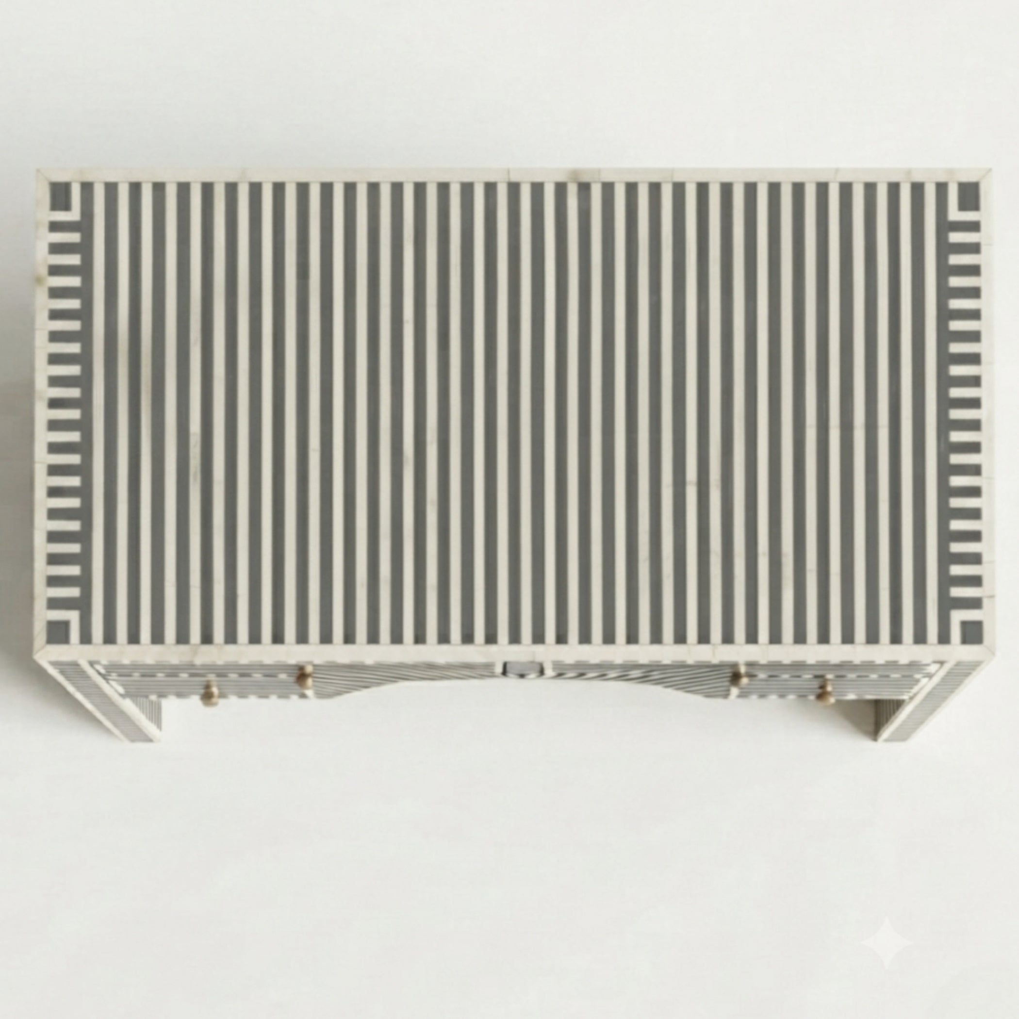 A rectangular console table with a top covered in vertical black and white stripes, featuring a white frame and small gold-toned hardware on the front.