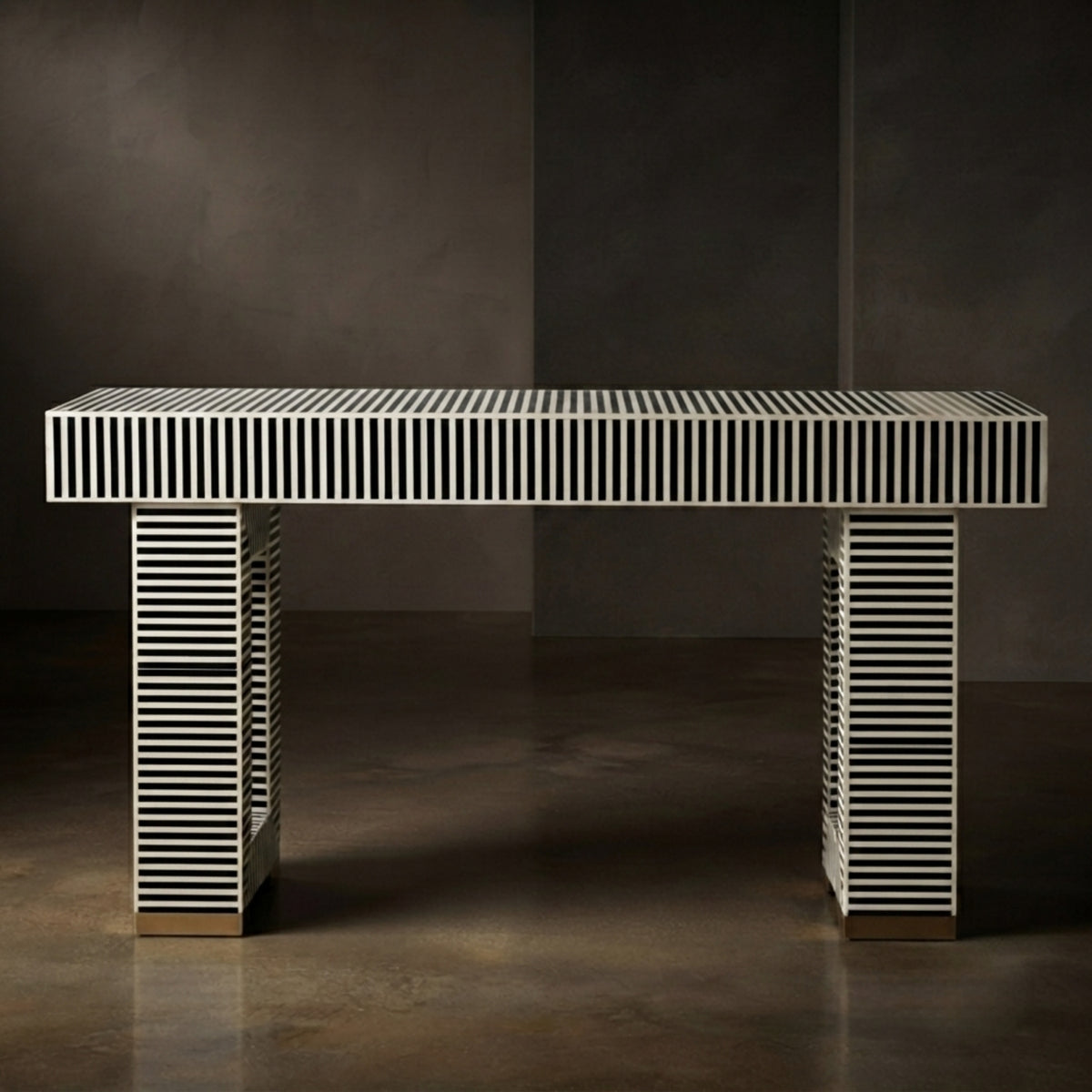 A modern rectangular console table with a white top and legs featuring black and white horizontal striping, set against a dark gray studio background.