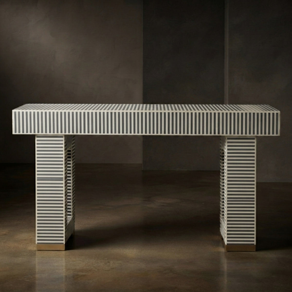 A modern rectangular console table with a white top and legs featuring vertical black stripes, set against a dark gray studio background.